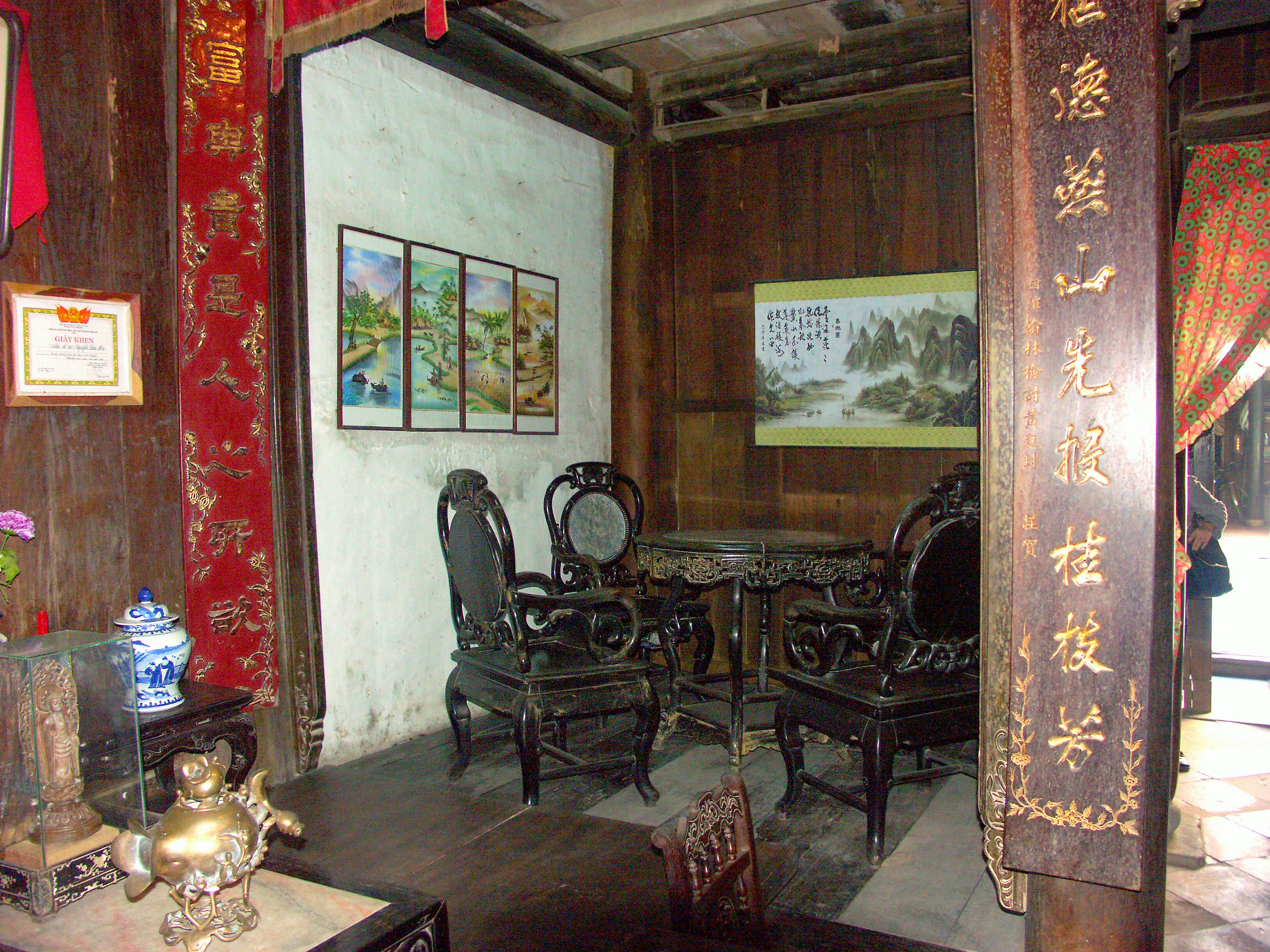 Pemandangan interior dengan furnitur tradisional dan lukisan di dinding kayu