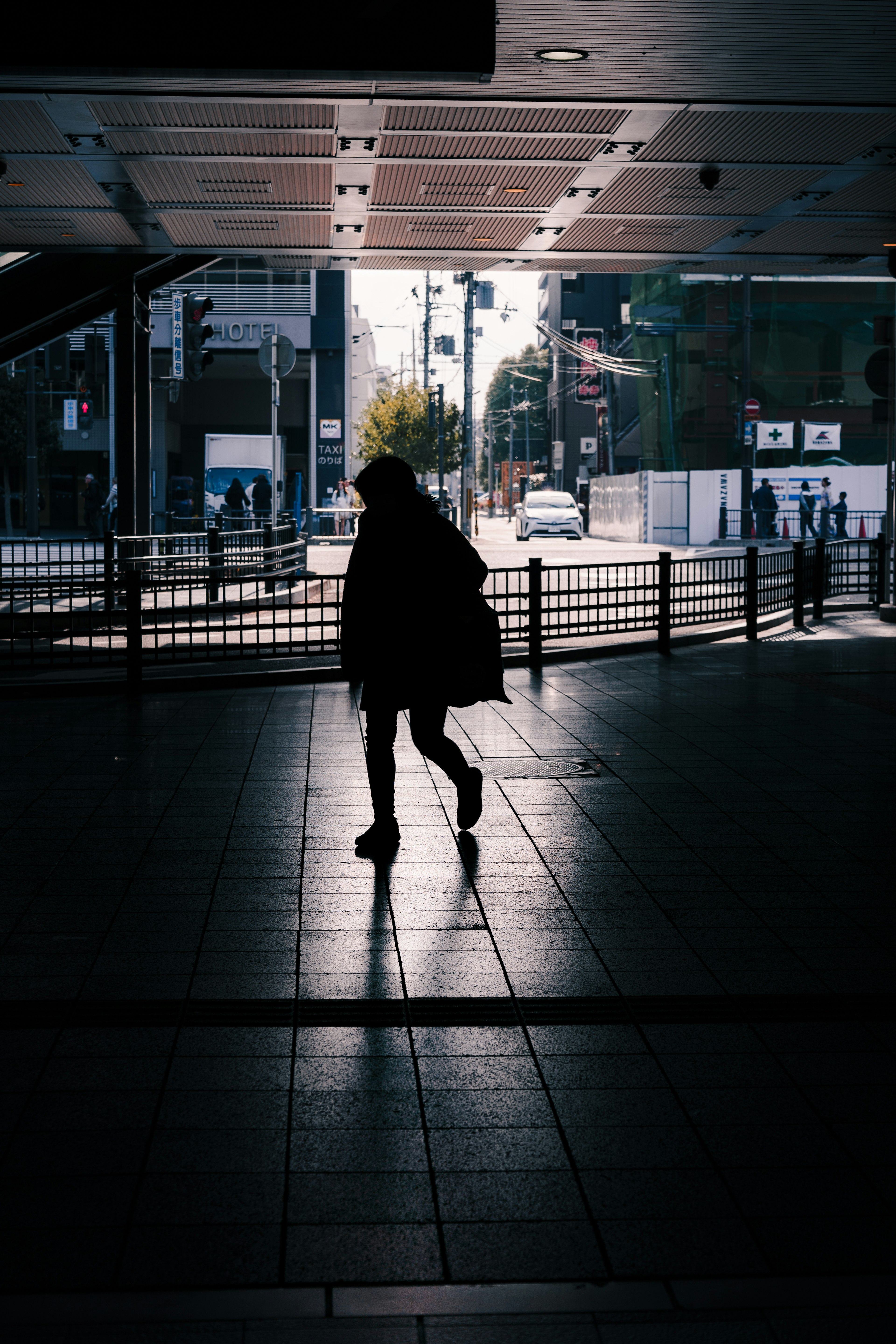 Silhouette of a person walking in a station with urban scenery