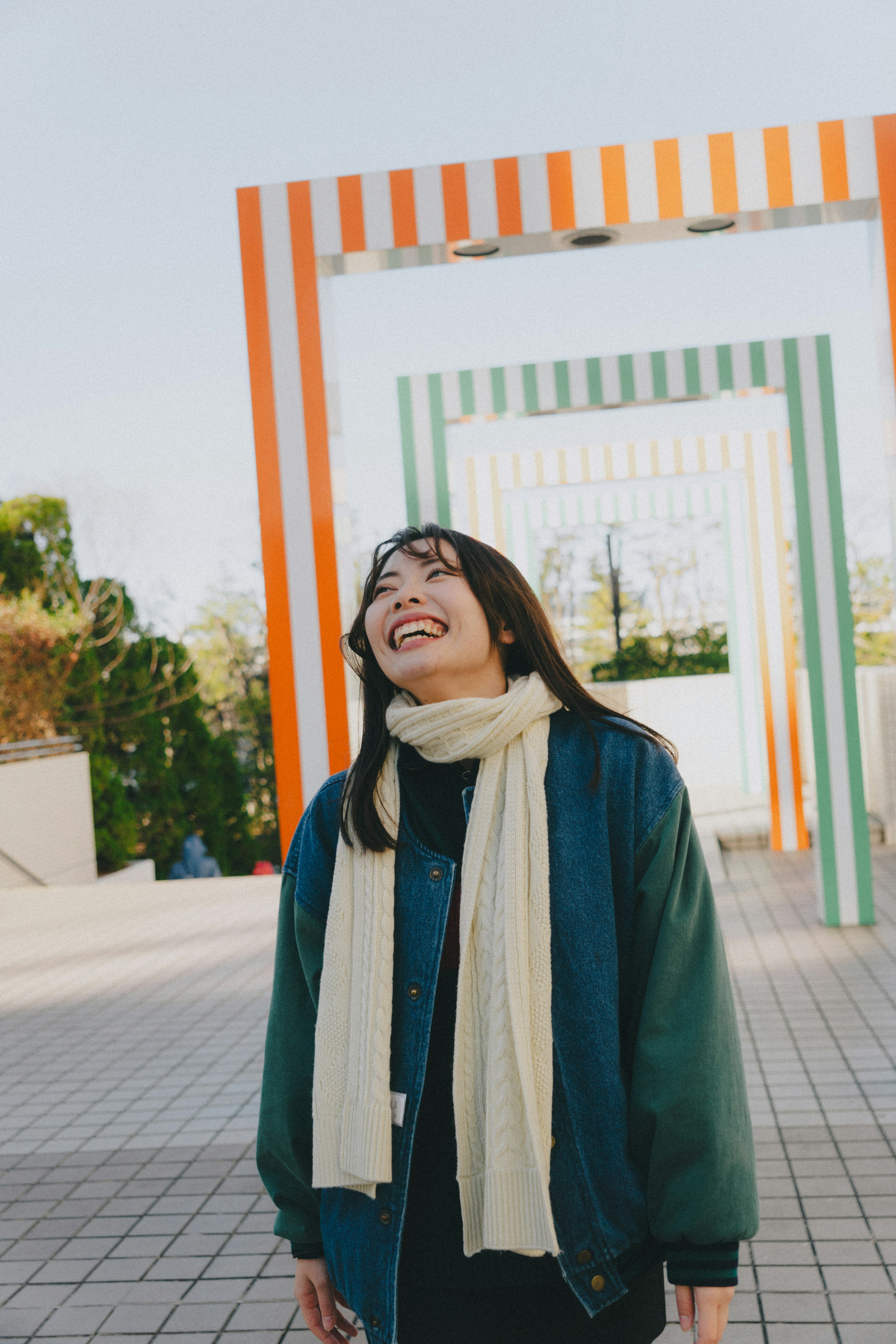 Una mujer sonriendo de pie entre arcos de colores