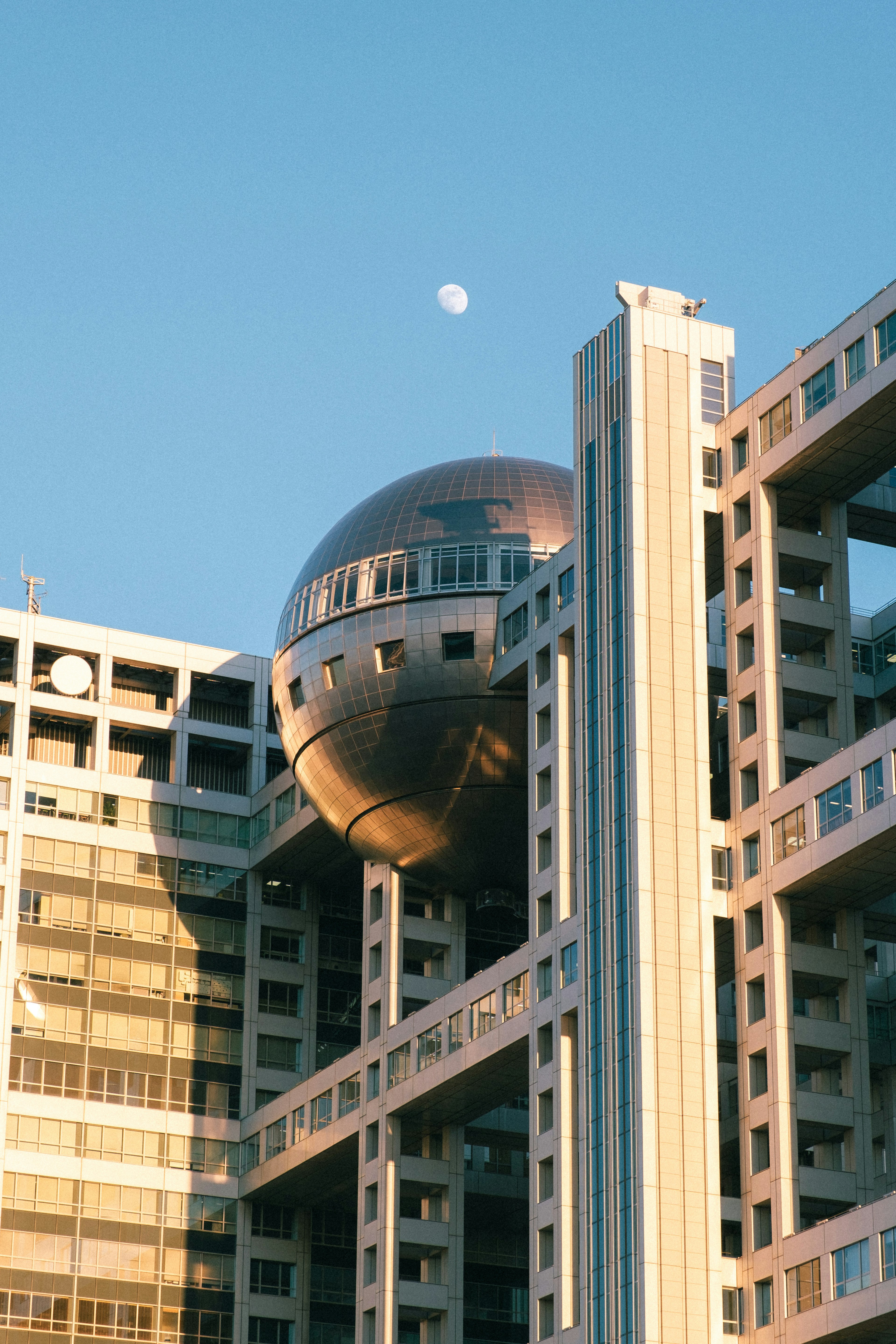 青空の下にある未来的な建物と銀色の球体