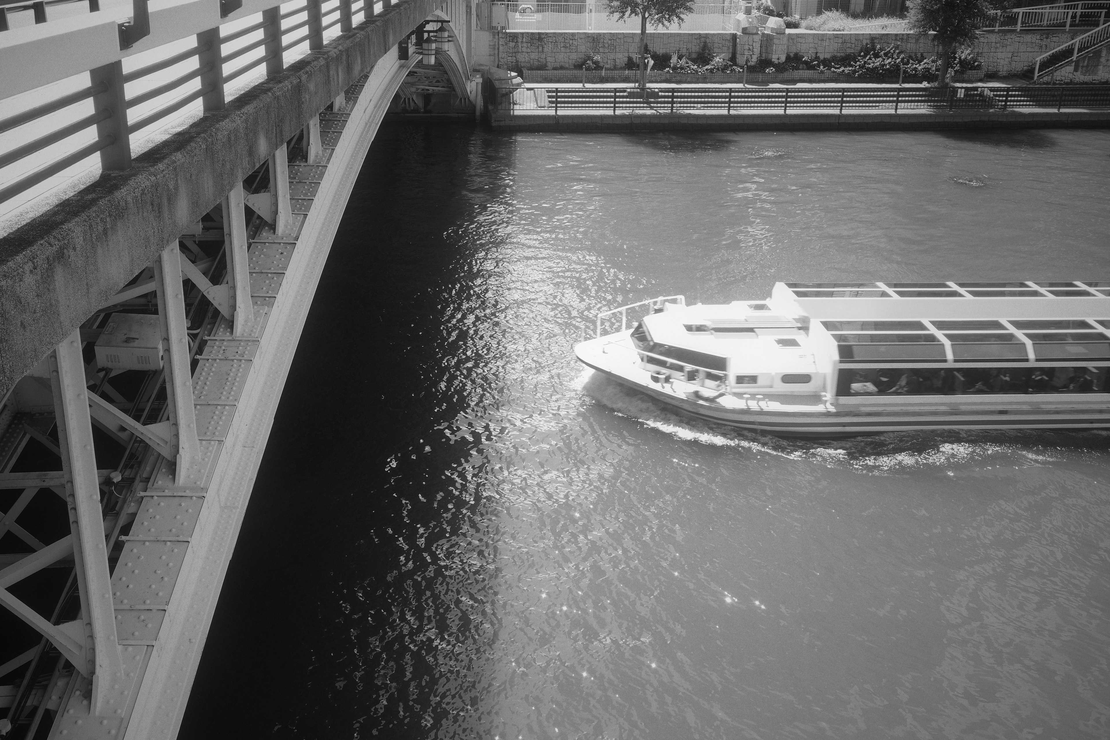 Vue en noir et blanc d'un bateau sur la rivière sous un pont