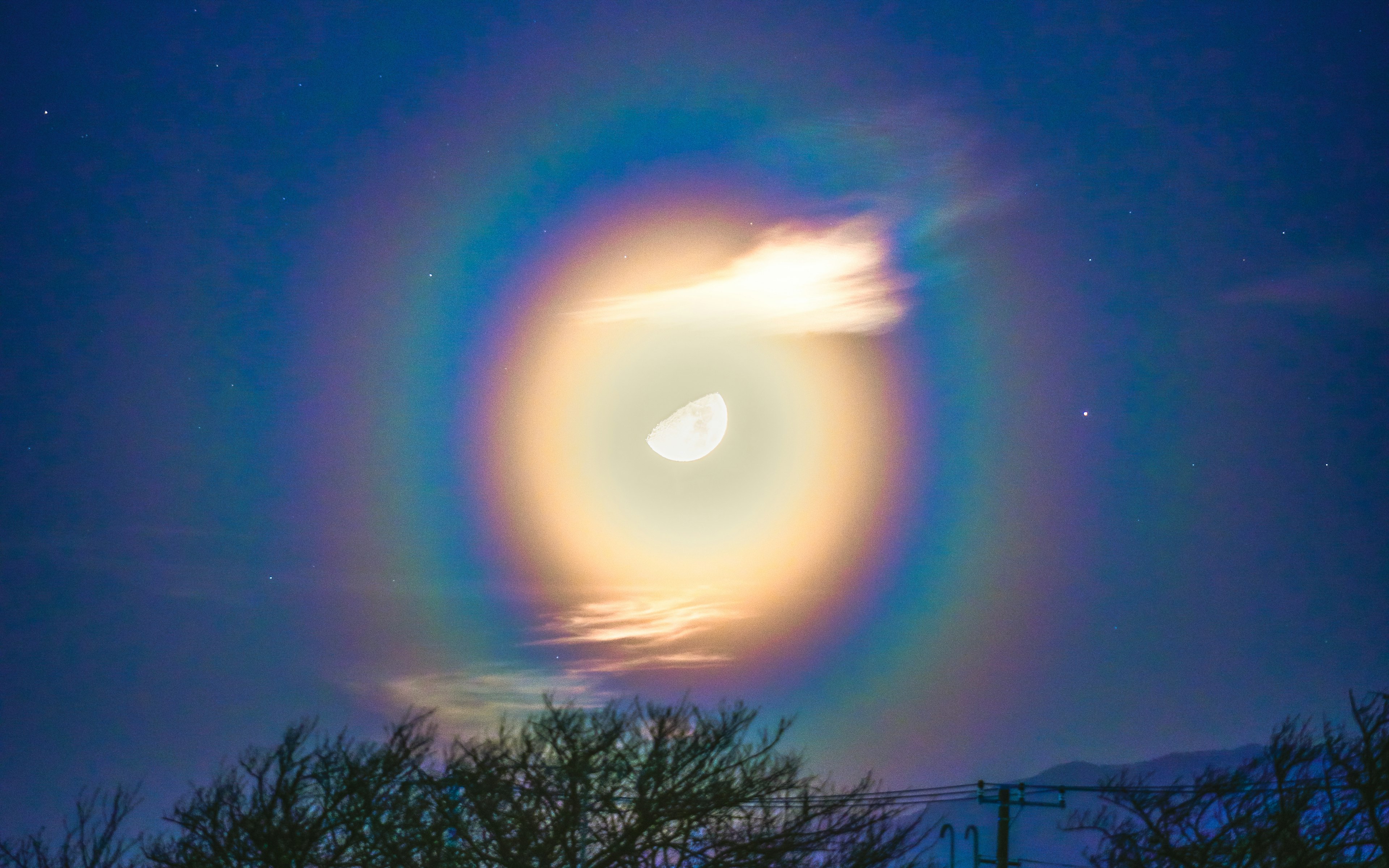 夜空中巨大的月亮周圍環繞著五彩的光環