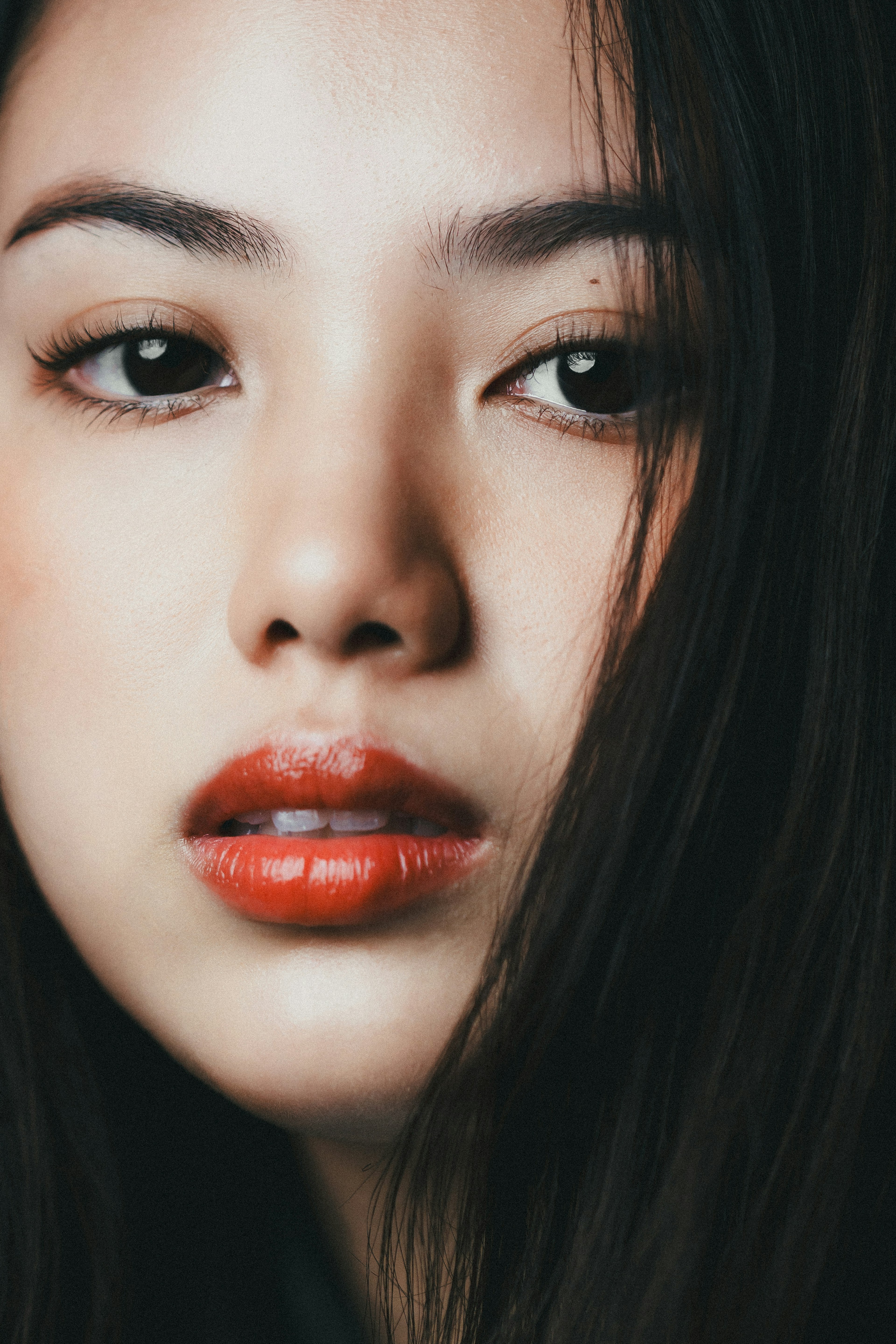 Close-up wajah wanita cantik dengan riasan alami dan bibir merah cerah