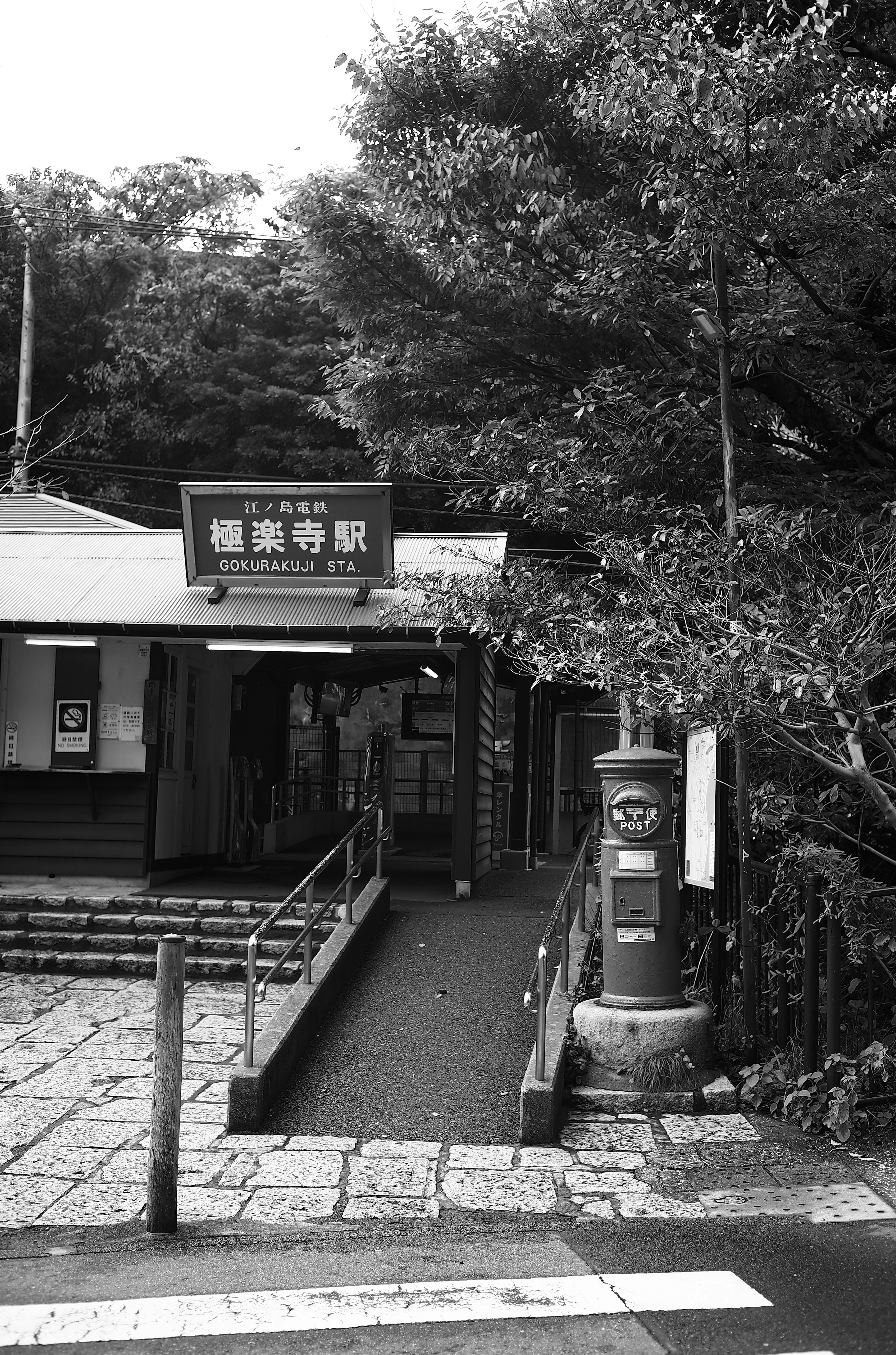 Foto hitam putih dari pintu masuk stasiun kecil dengan kotak pos