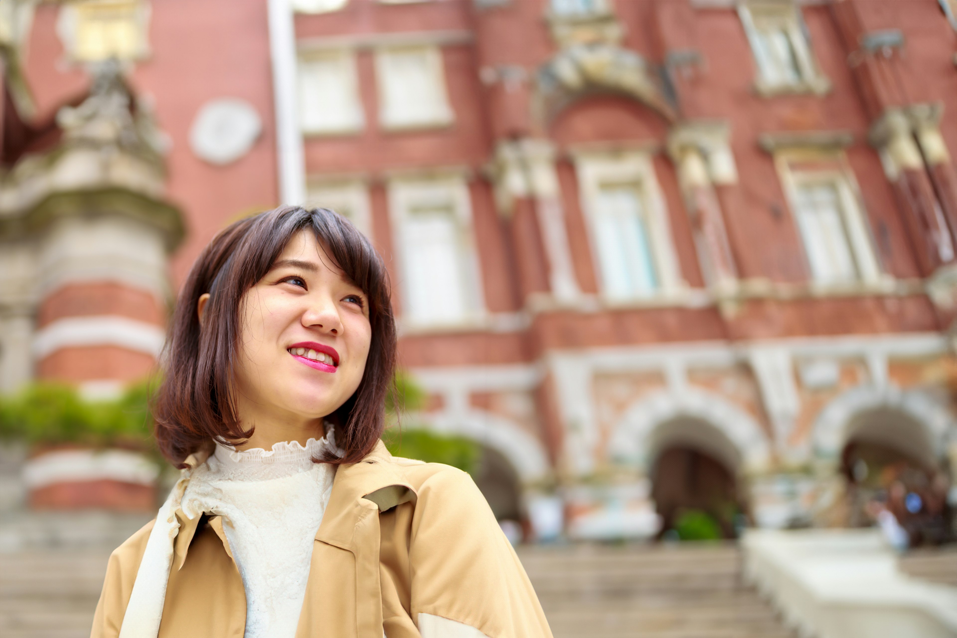 미소 짓고 있는 여성과 배경의 빨간 벽돌 건물