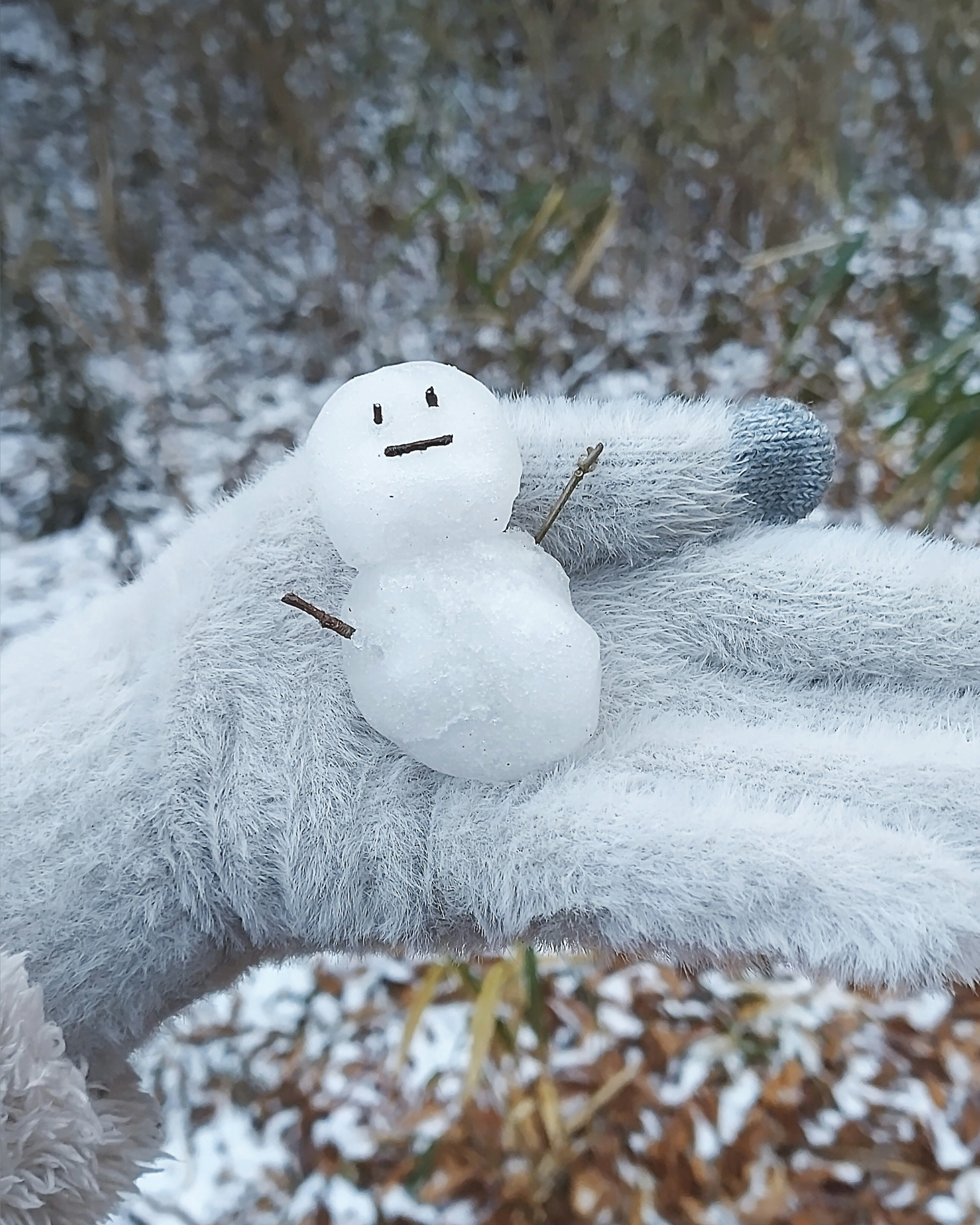 Un pequeño muñeco de nieve en una mano sobre un fondo nevado