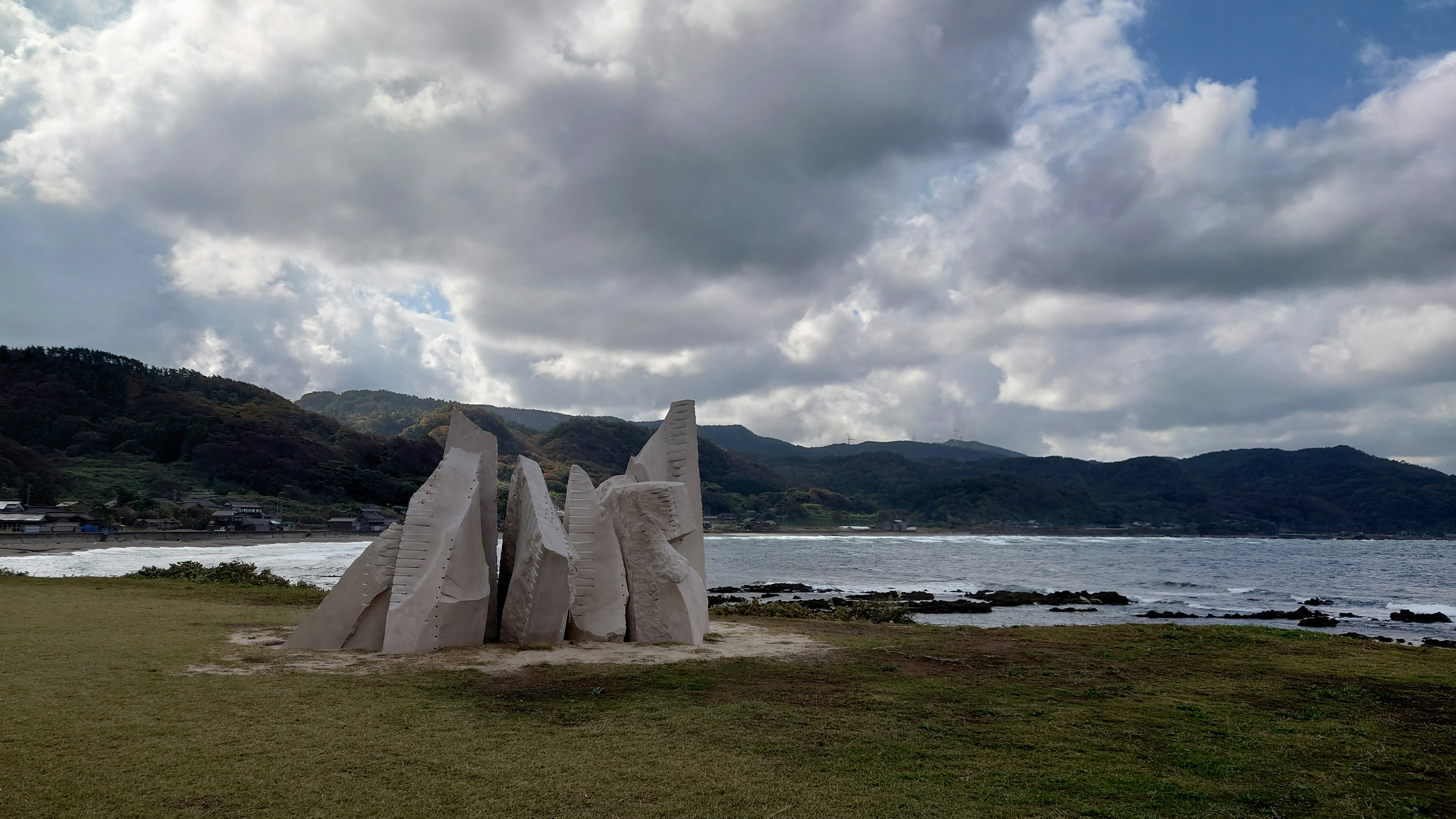 Sculpture blanche au bord de la mer avec un ciel nuageux