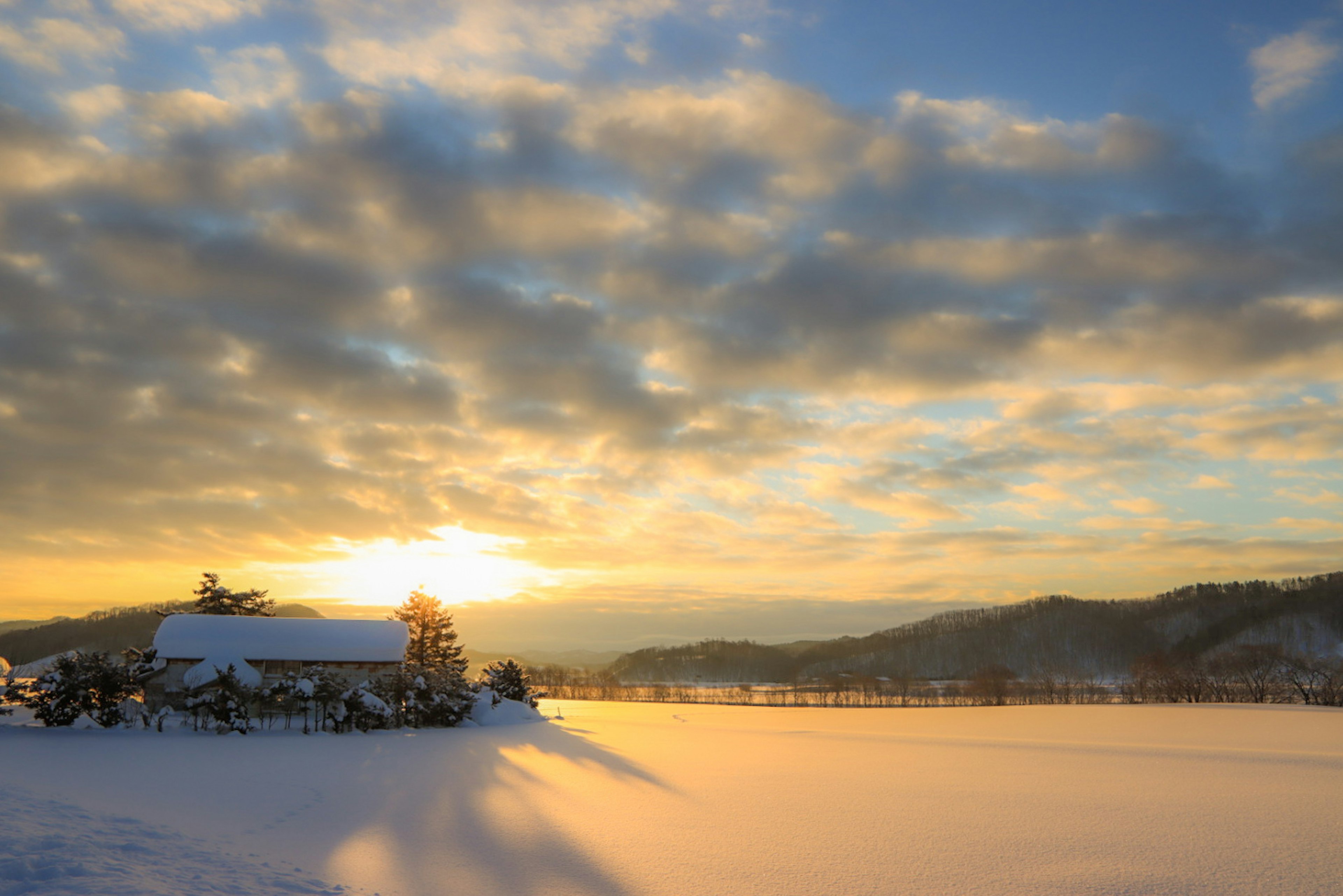 Snow-covered lake with mountains and a sunset sky