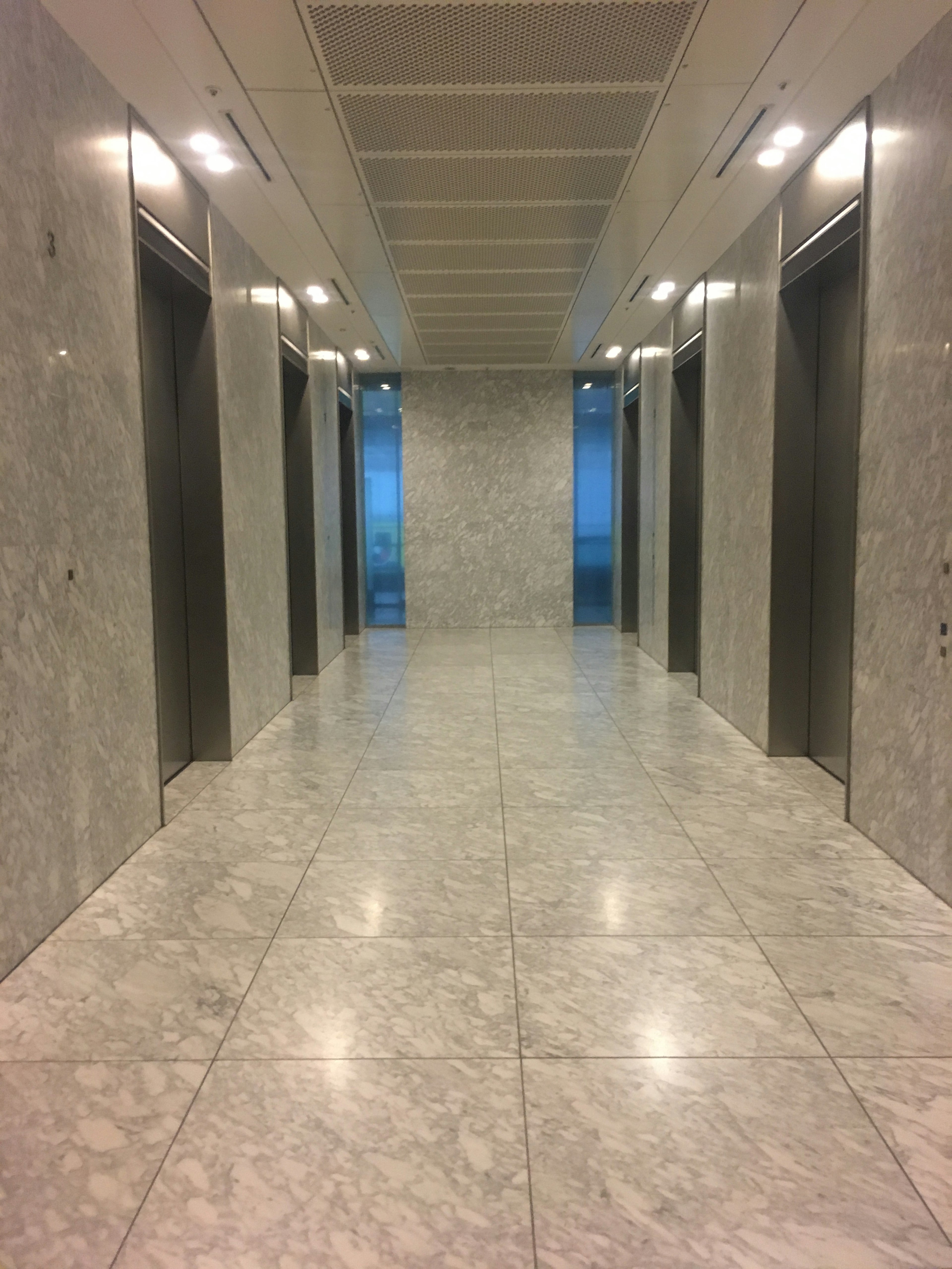 A hallway with elevator doors and marble flooring