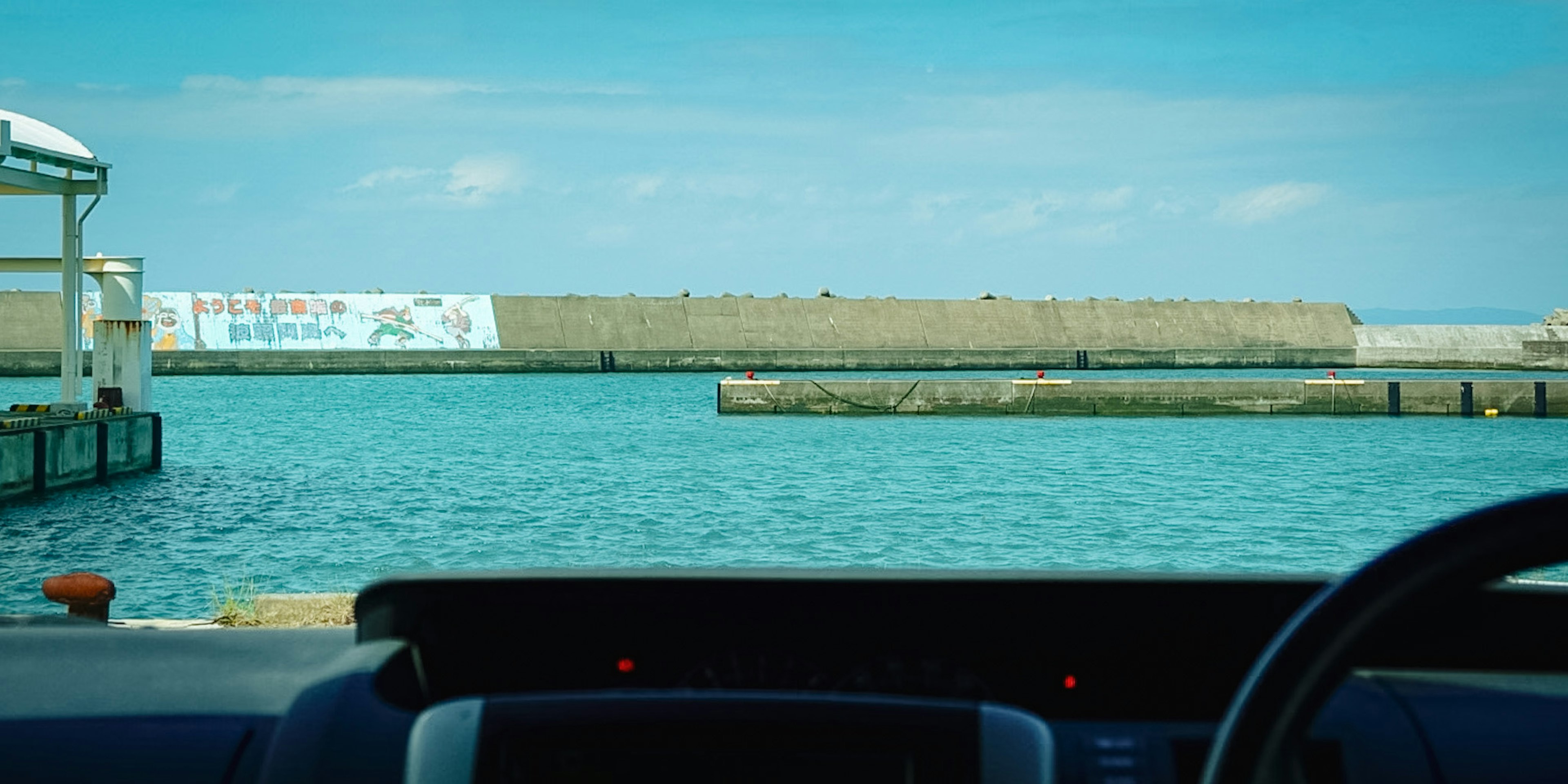 Vista del mare e del molo dal cruscotto di un'auto