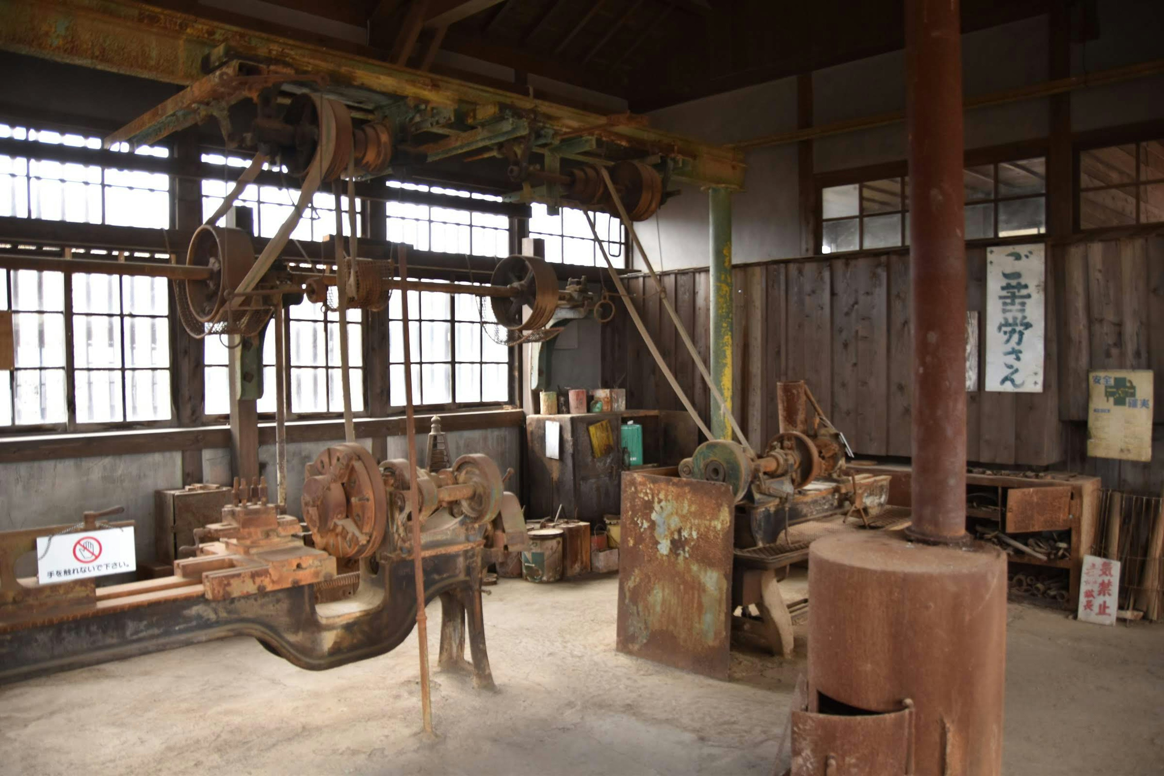 Interno di una vecchia fabbrica con macchinari pesanti e banchi di lavoro in legno