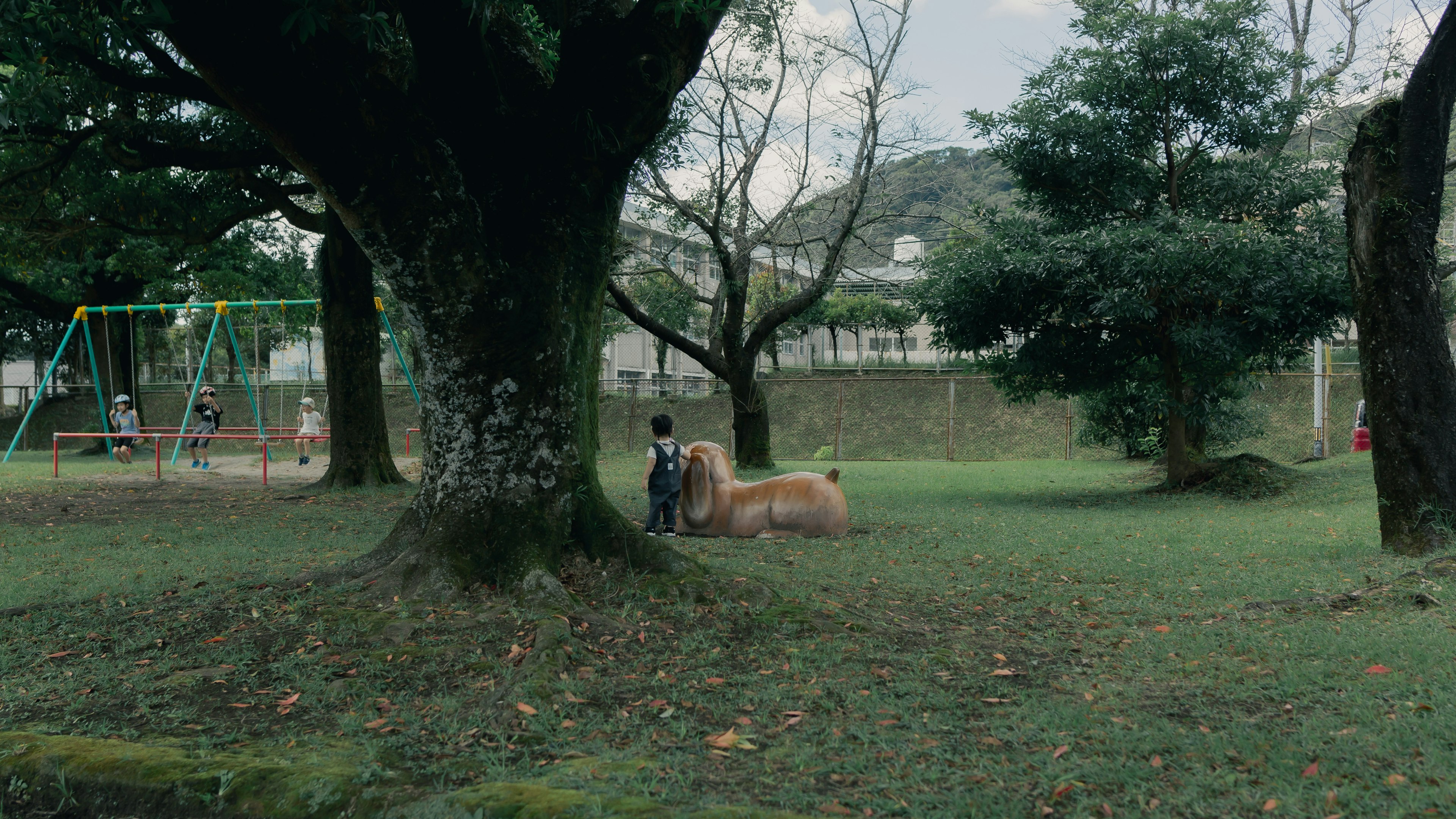 Un niño jugando con un perro debajo de un gran árbol en un parque