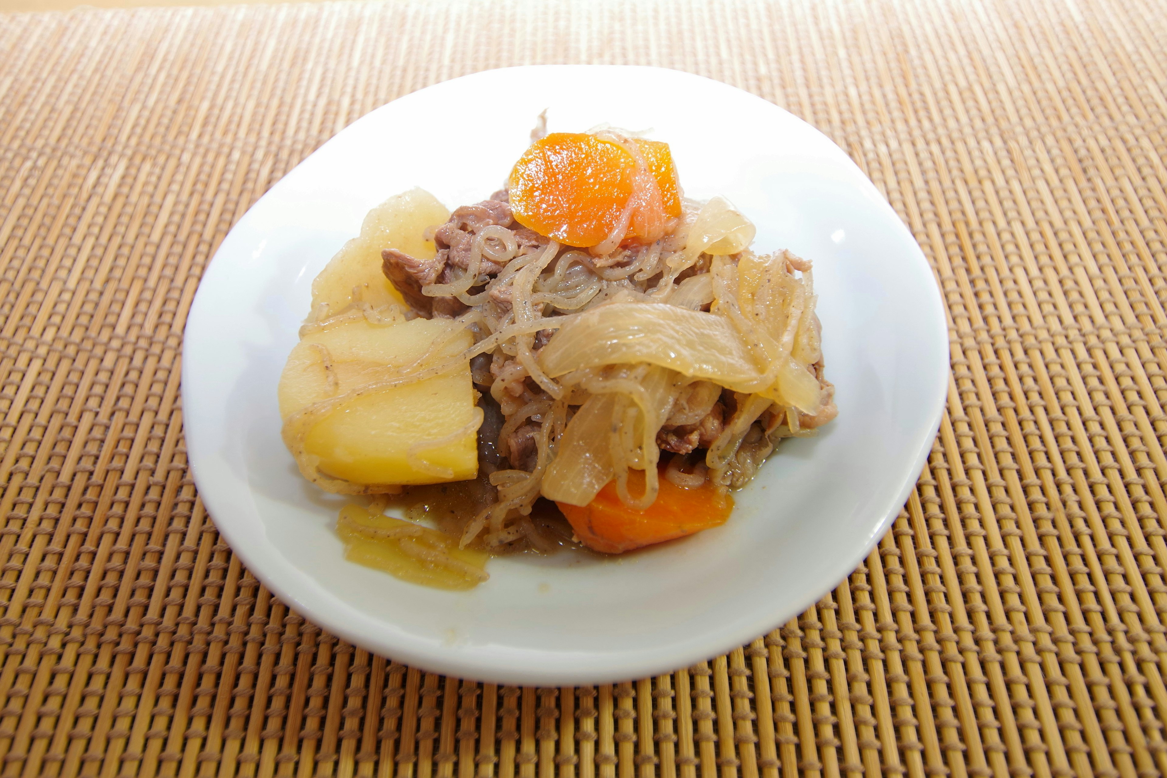 Un plato de nikujaga con patatas, zanahorias, cebollas y carne de res