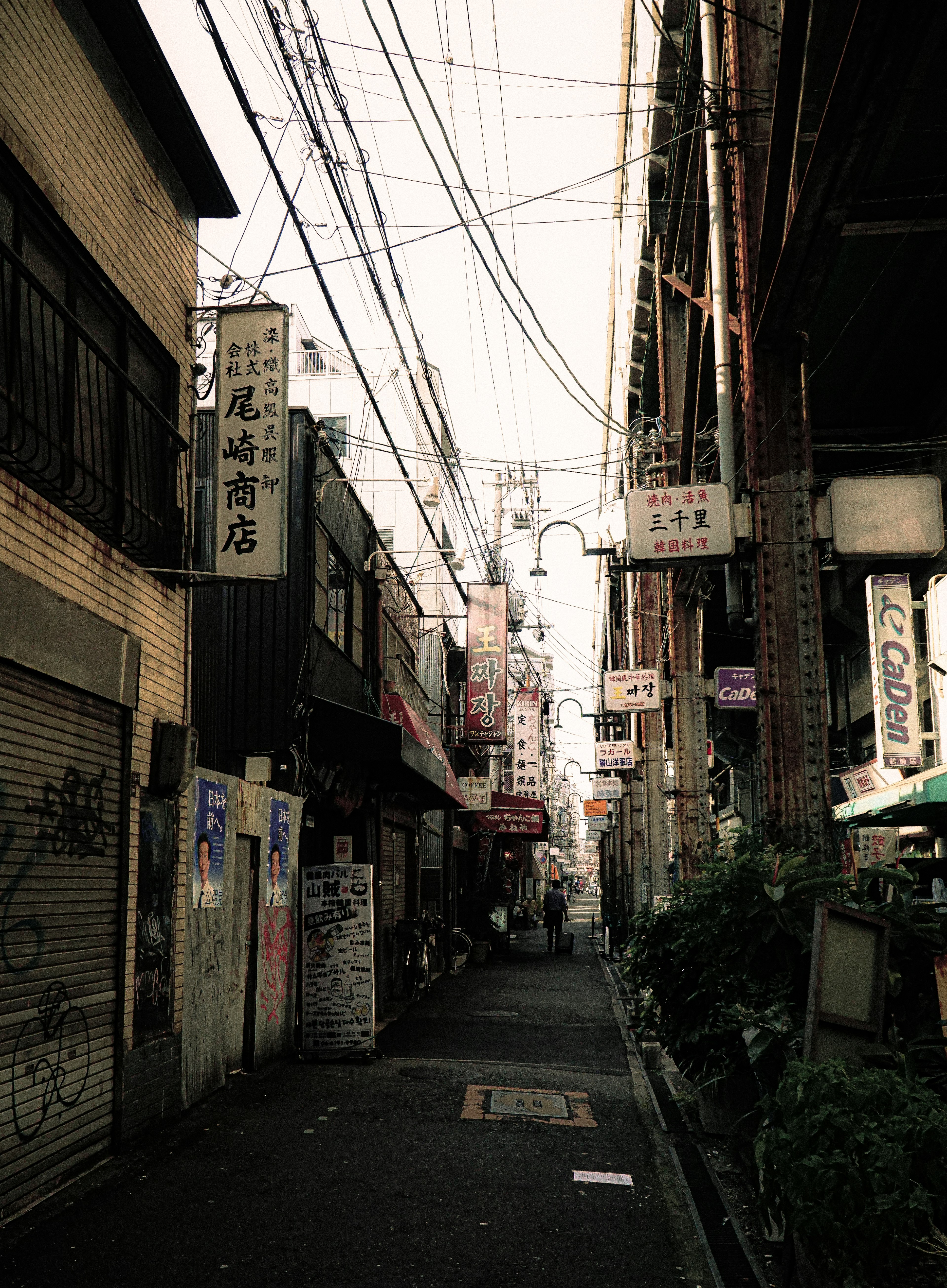 Narrow alley lined with shop signs and overhead power lines