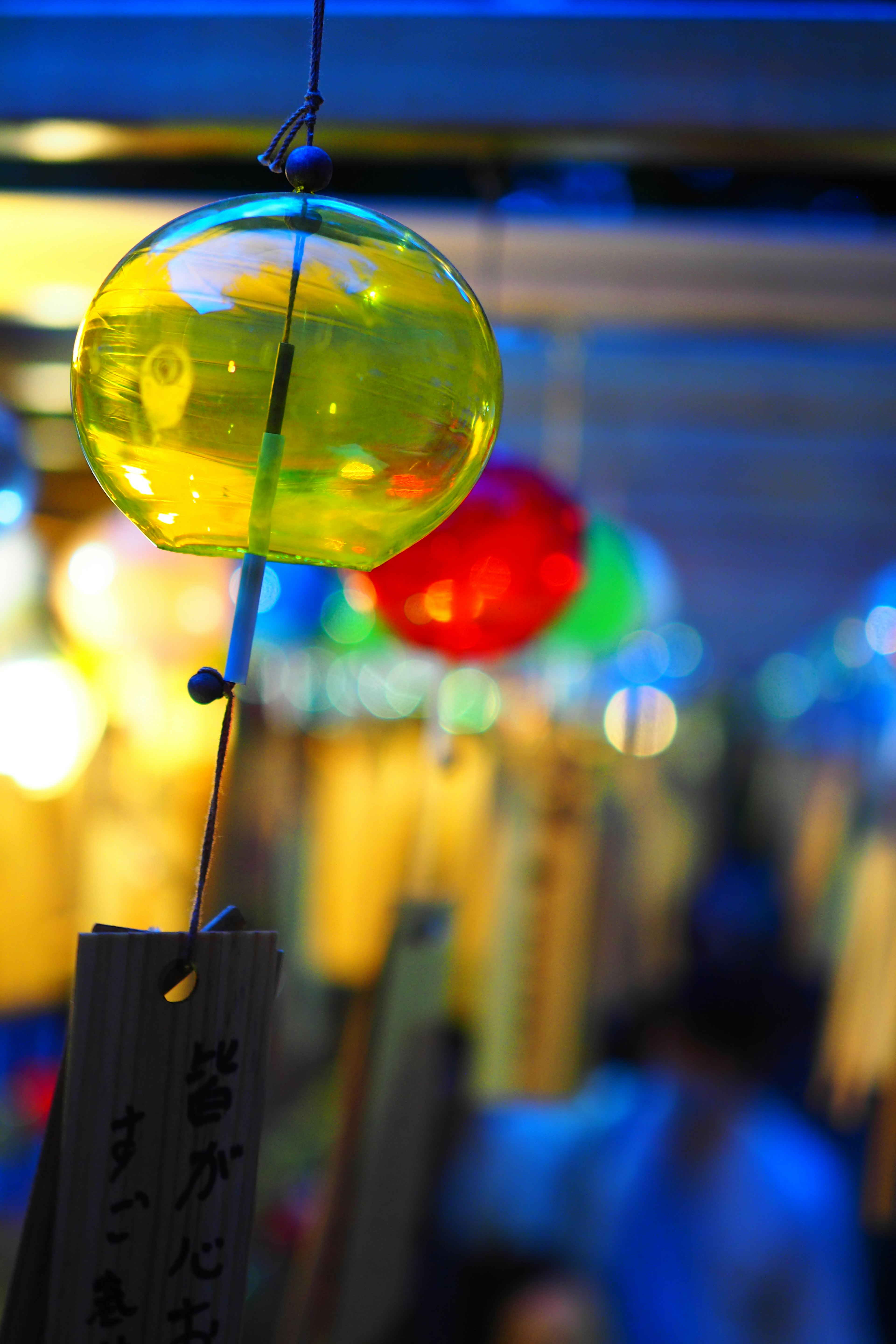 Colorful wind chimes hanging in a vibrant setting with a prominent yellow chime