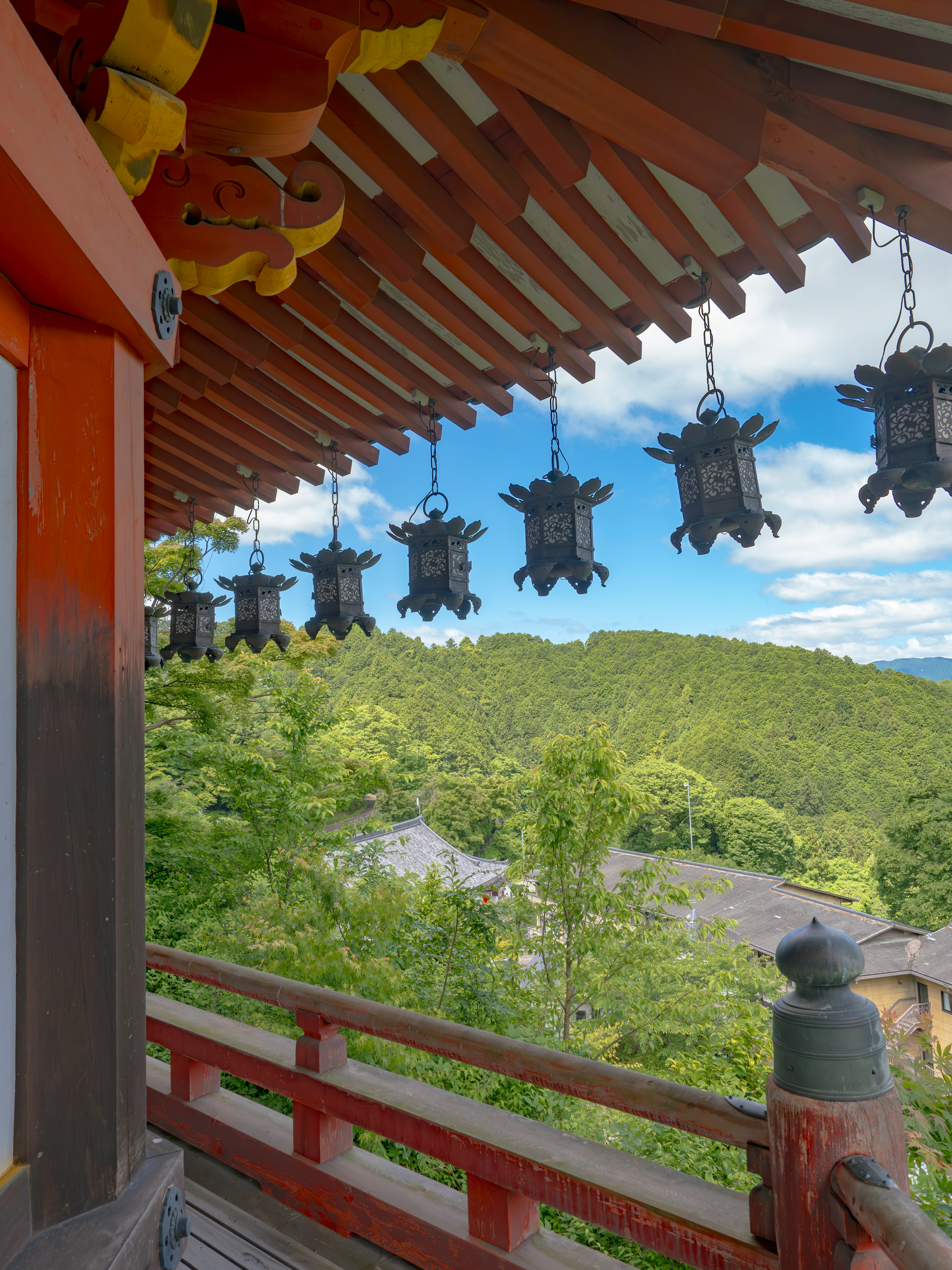 Temple roof with lanterns and lush green mountains in the background