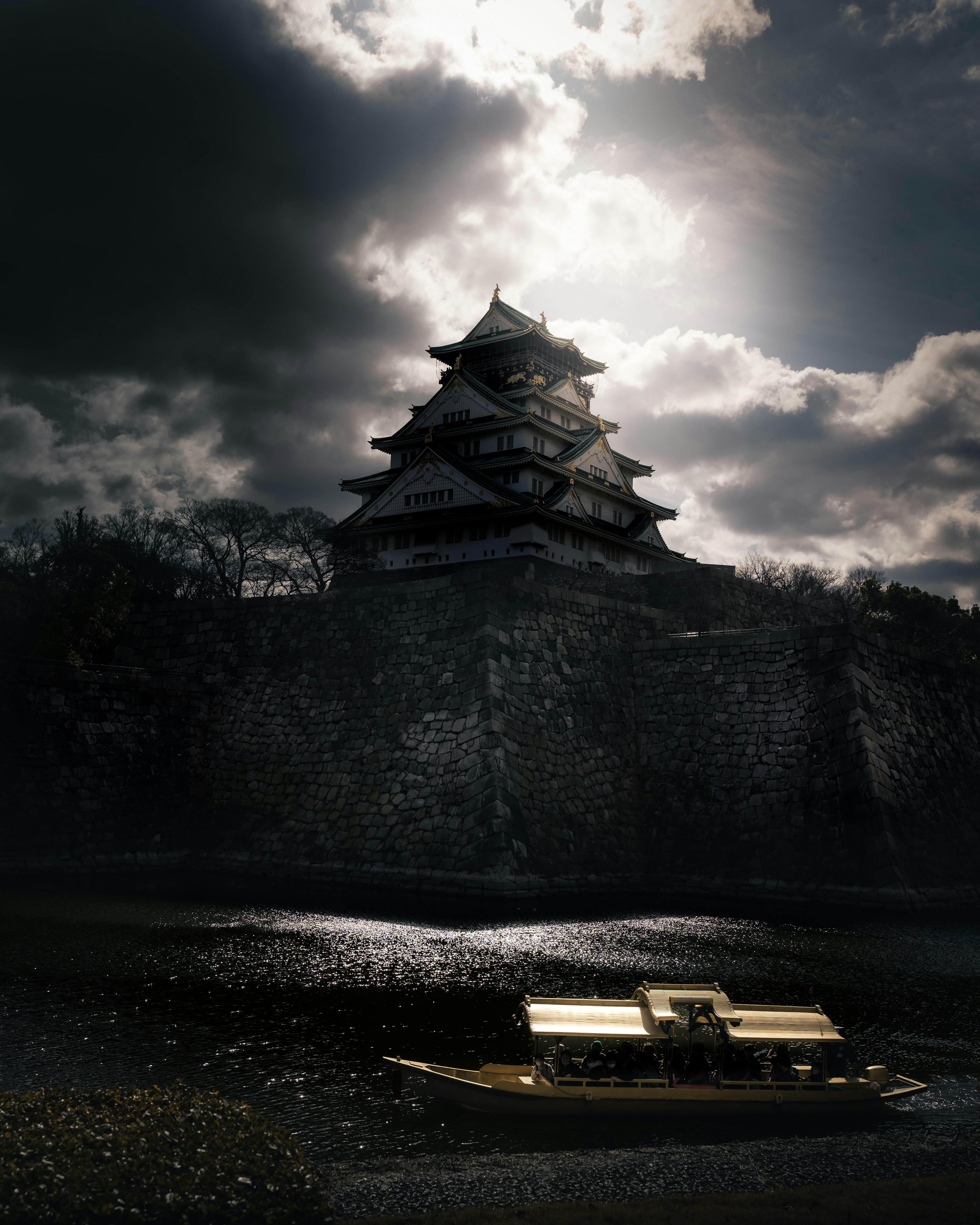 A castle towering under a dark sky with a calm water surface in front