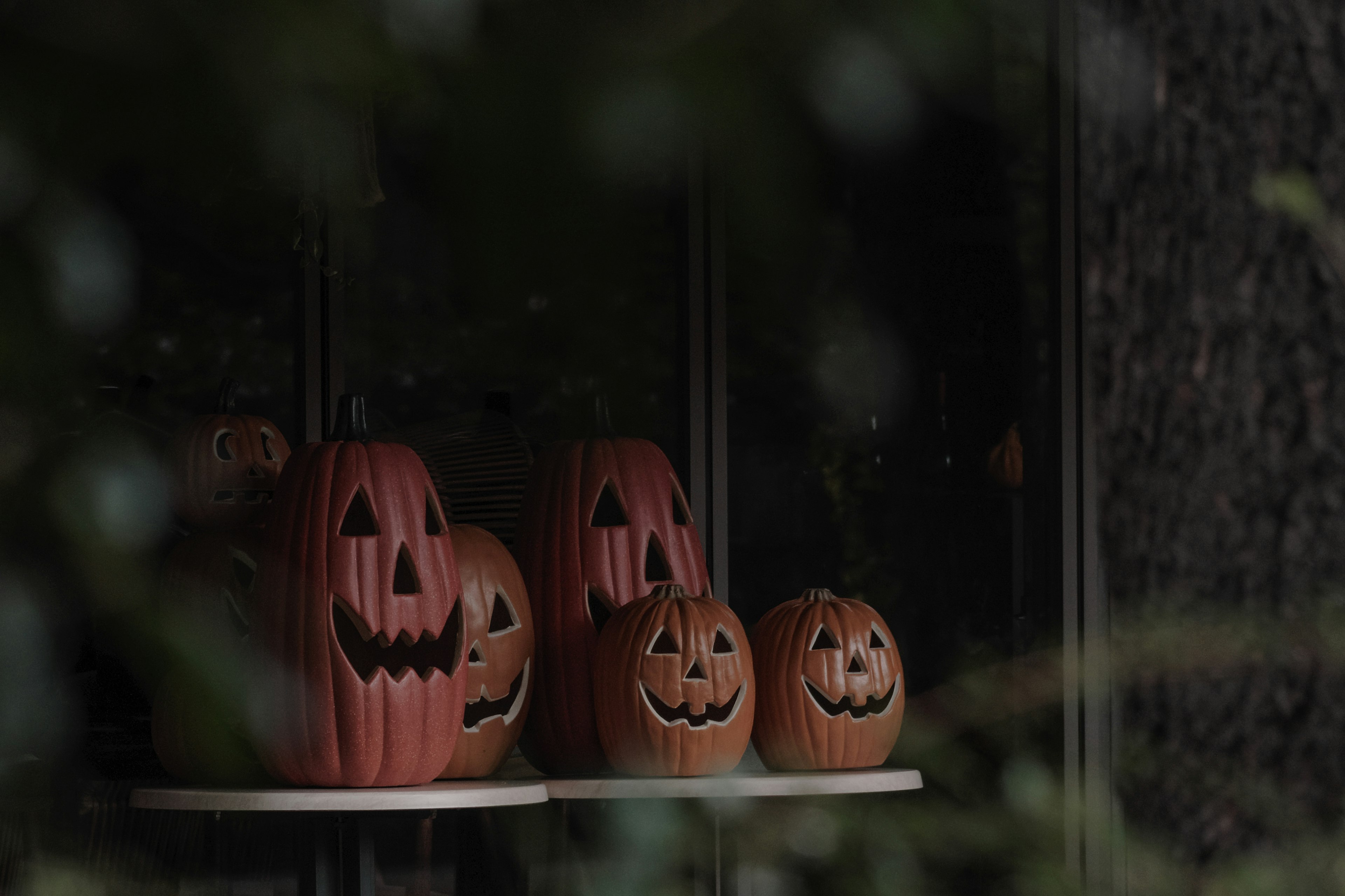 Halloween pumpkins displayed on a windowsill with a dark background