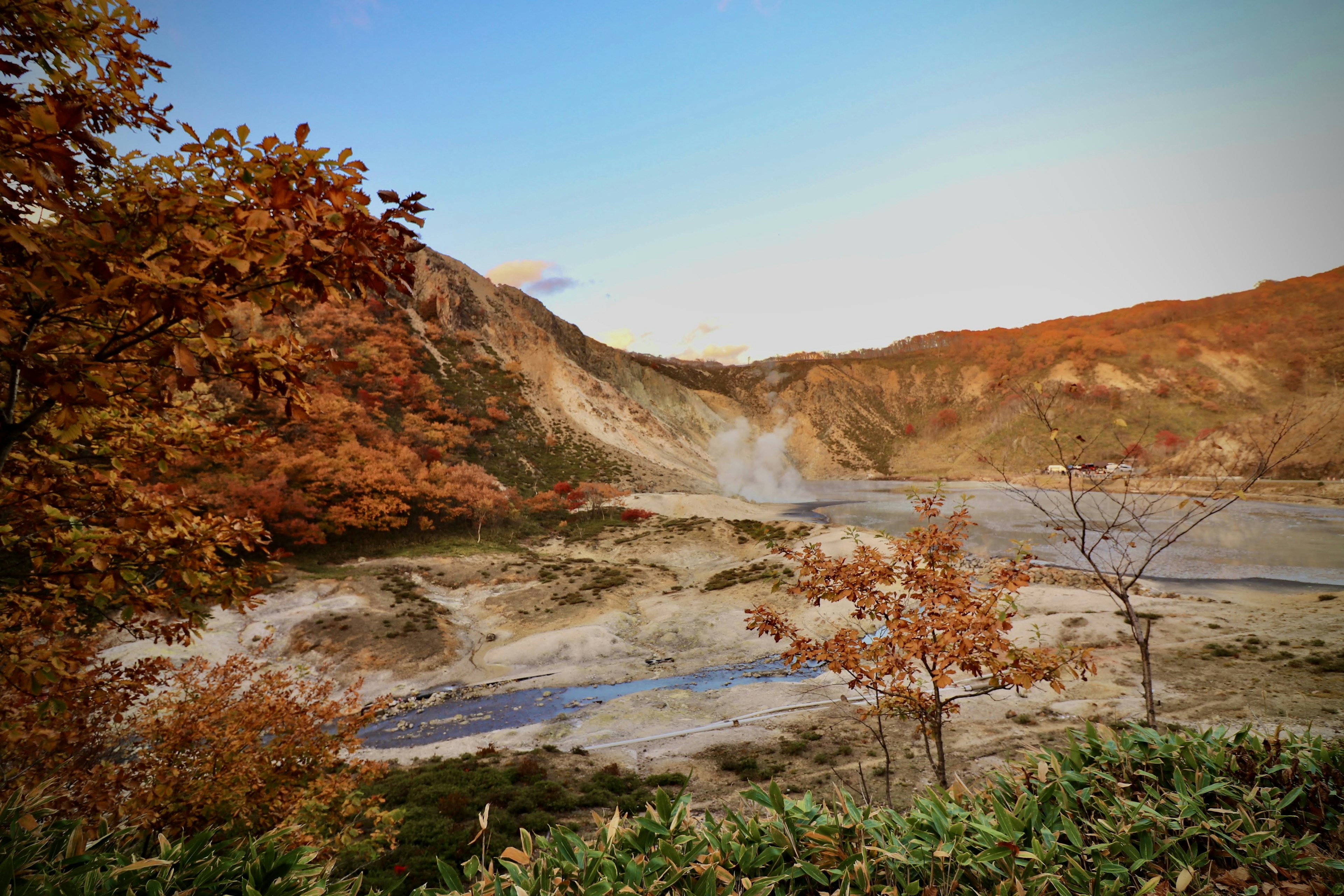 Vue pittoresque d'une zone thermale entourée de feuillage d'automne et d'un ciel calme