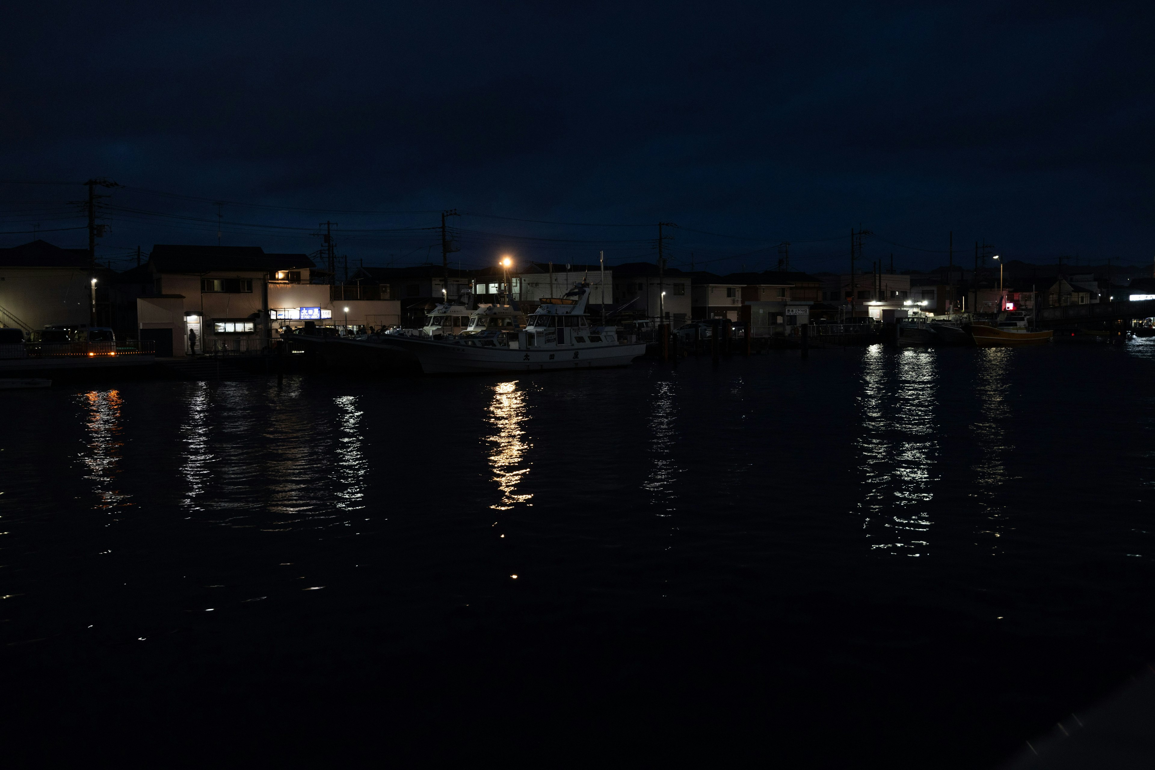 Nachtszene mit Reflexionen von Stadtlichtern auf dem Wasser und einem ruhigen Boot