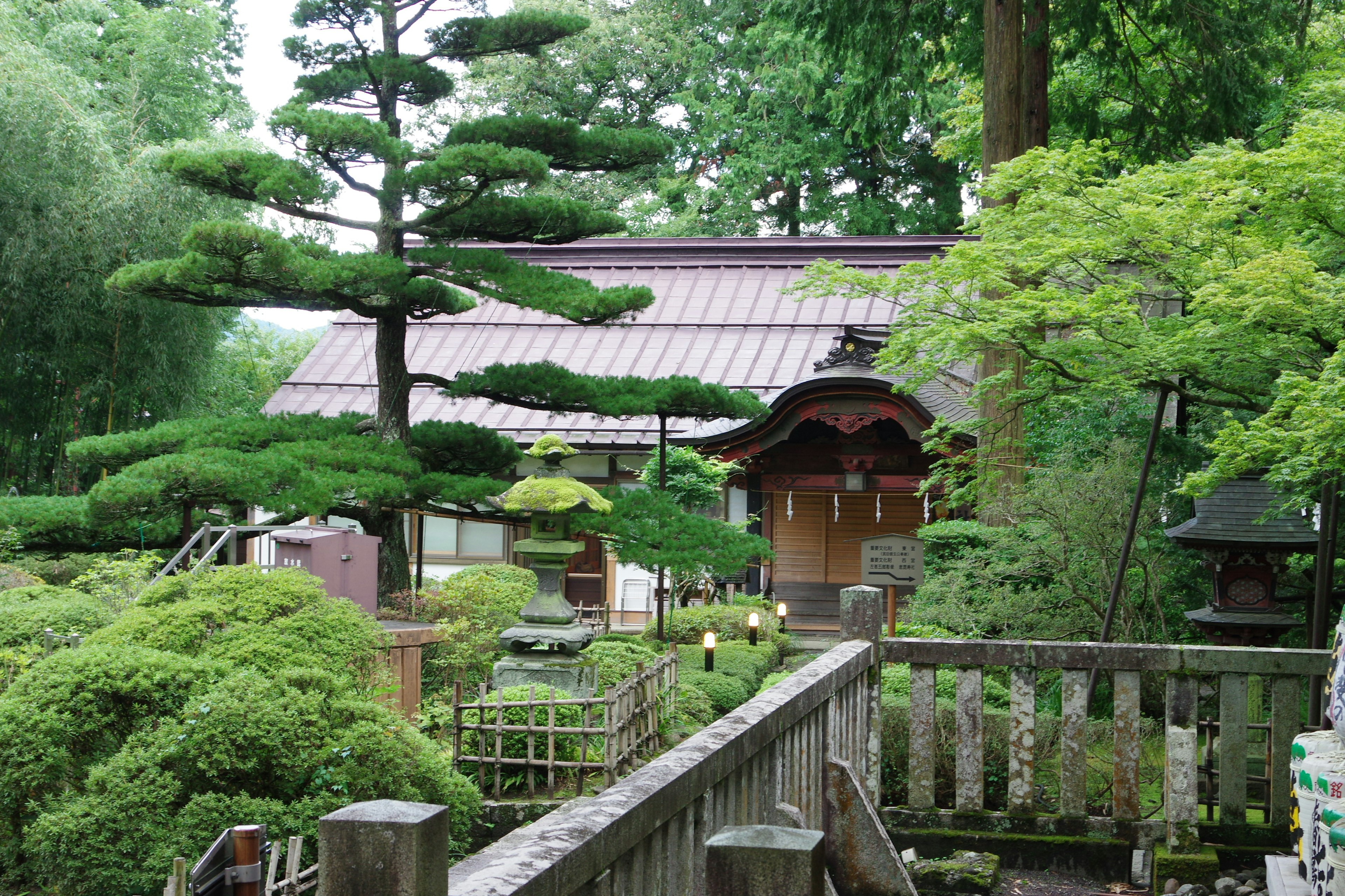 Traditionelles japanisches Haus umgeben von üppigem Grün und Kiefern