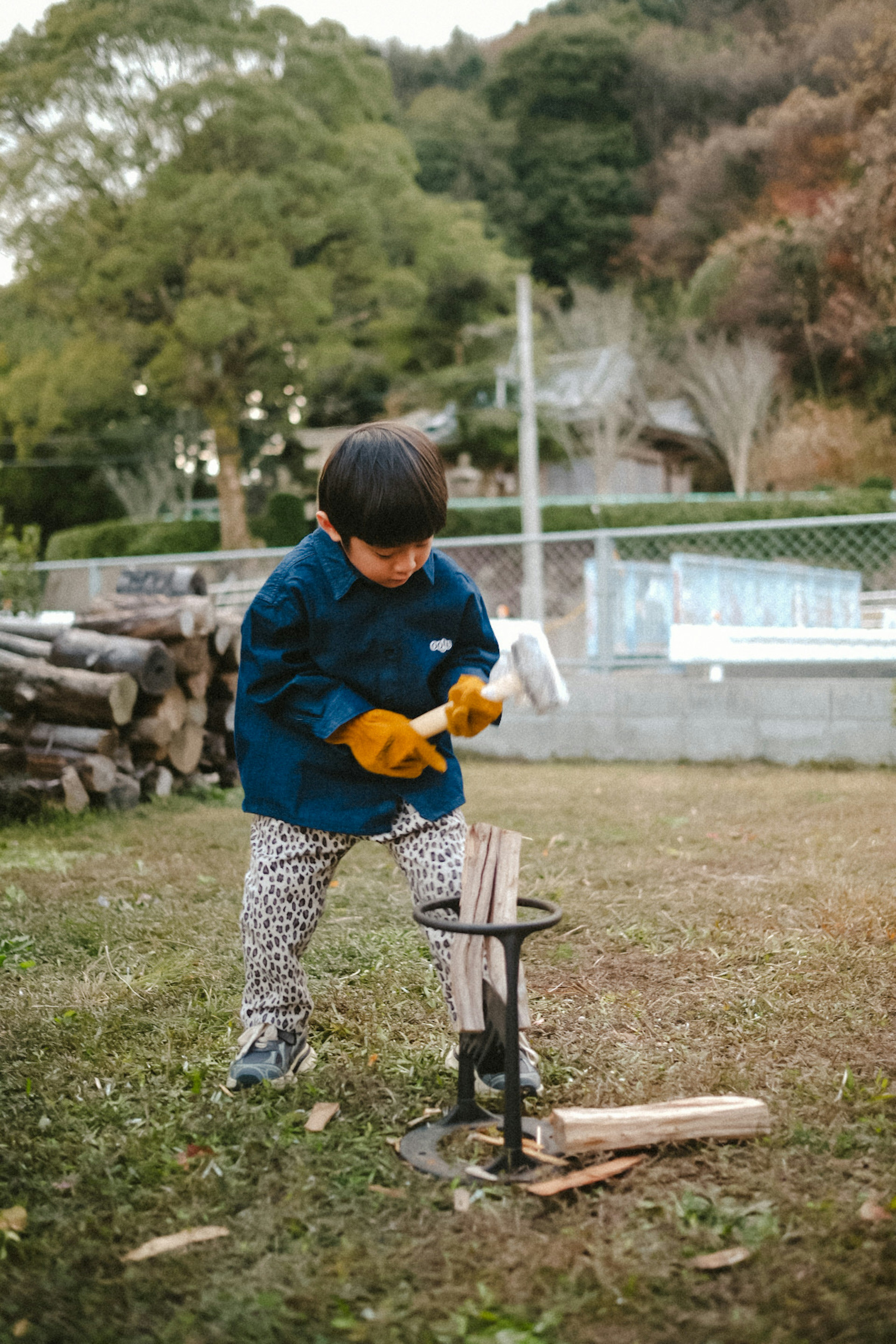 A child using a hammer to split wood outdoors