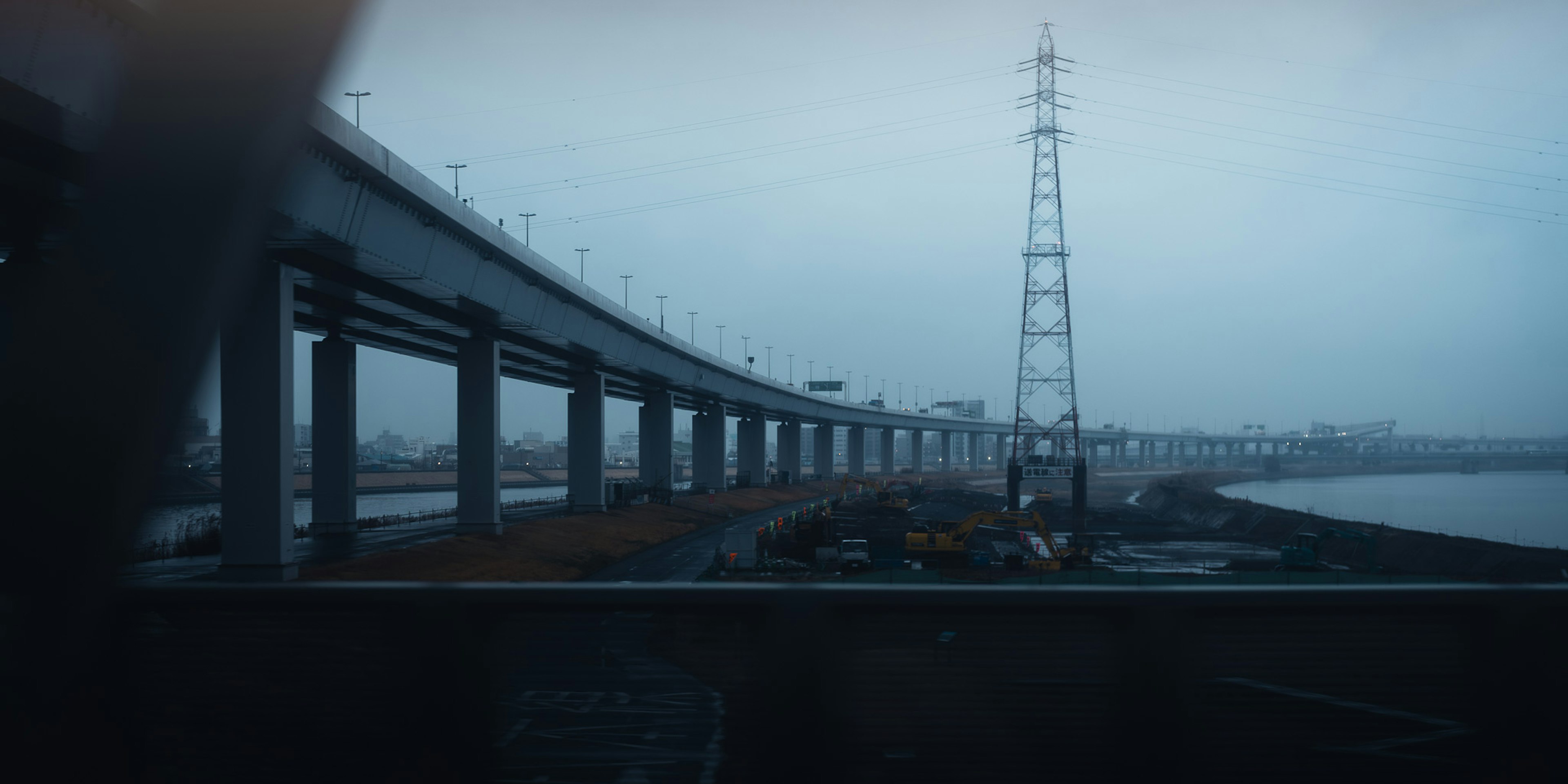 Vista de un puente y una torre de transmisión bajo un cielo sombrío