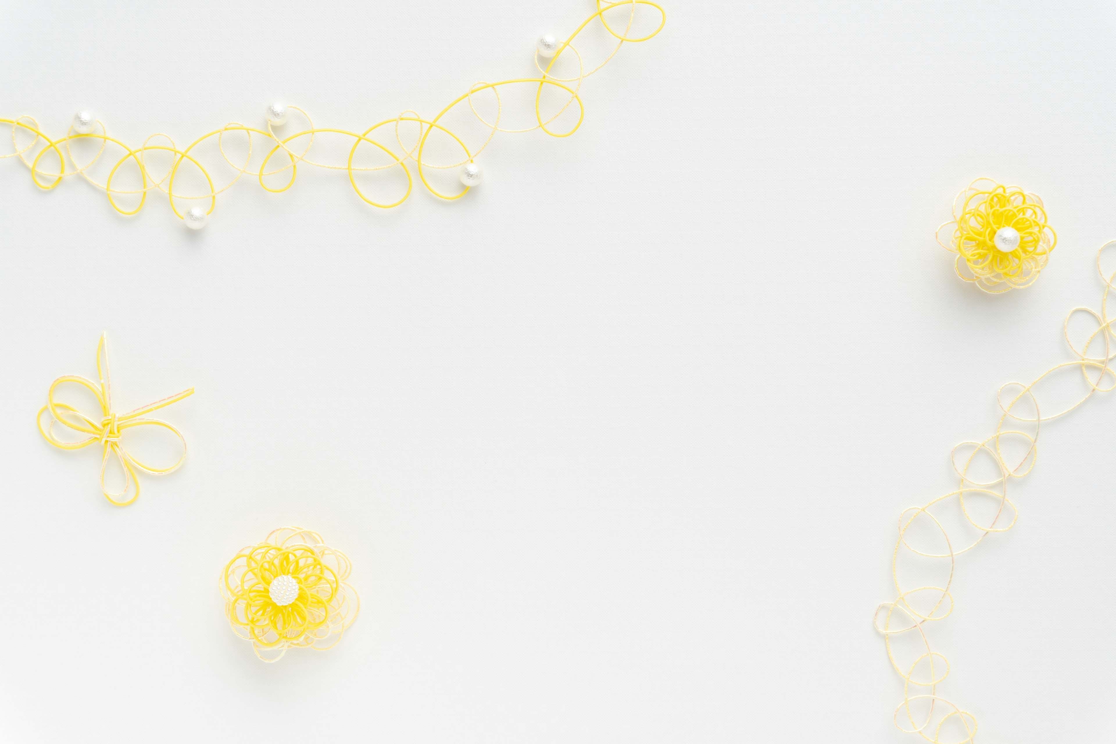 Image featuring yellow lace and bead decorations scattered on a white background