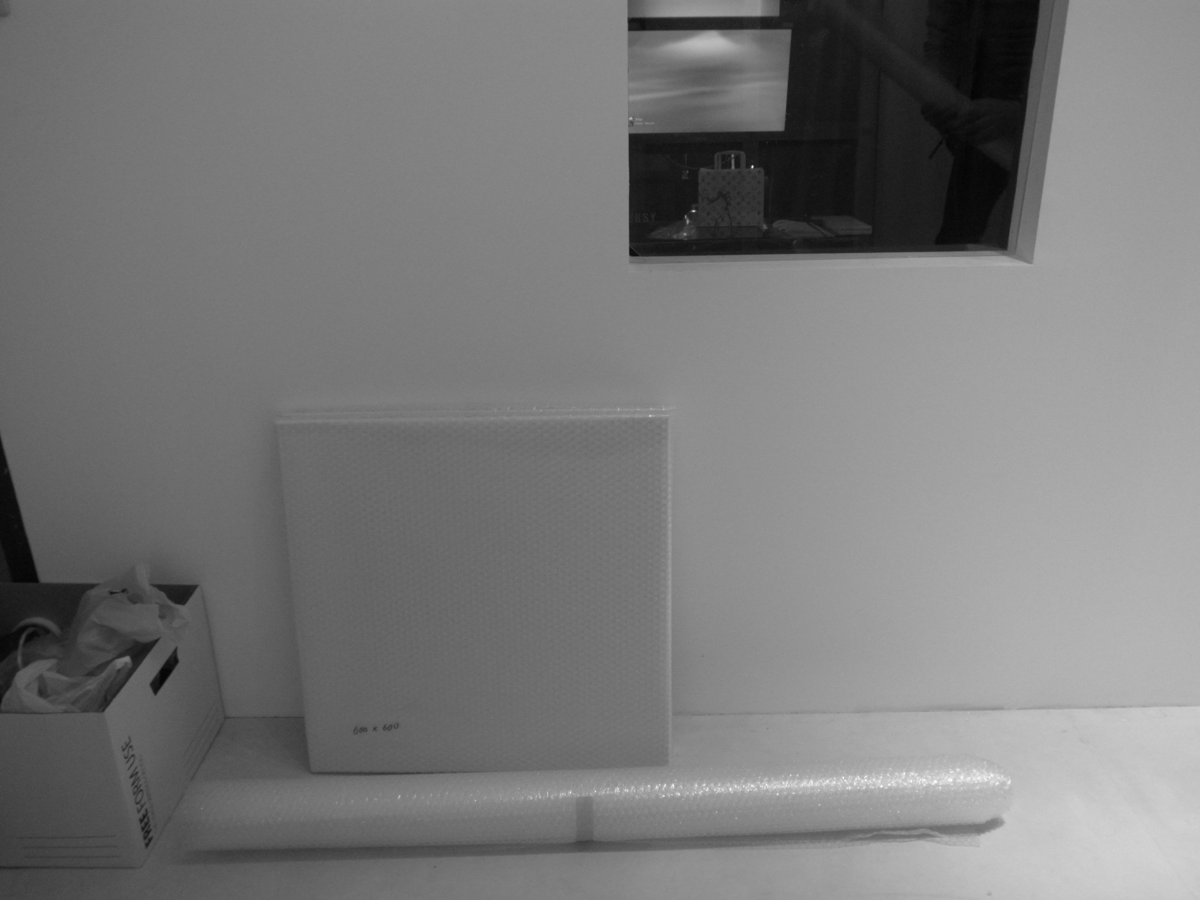 A simple interior corner with a box and rolled material against a white wall