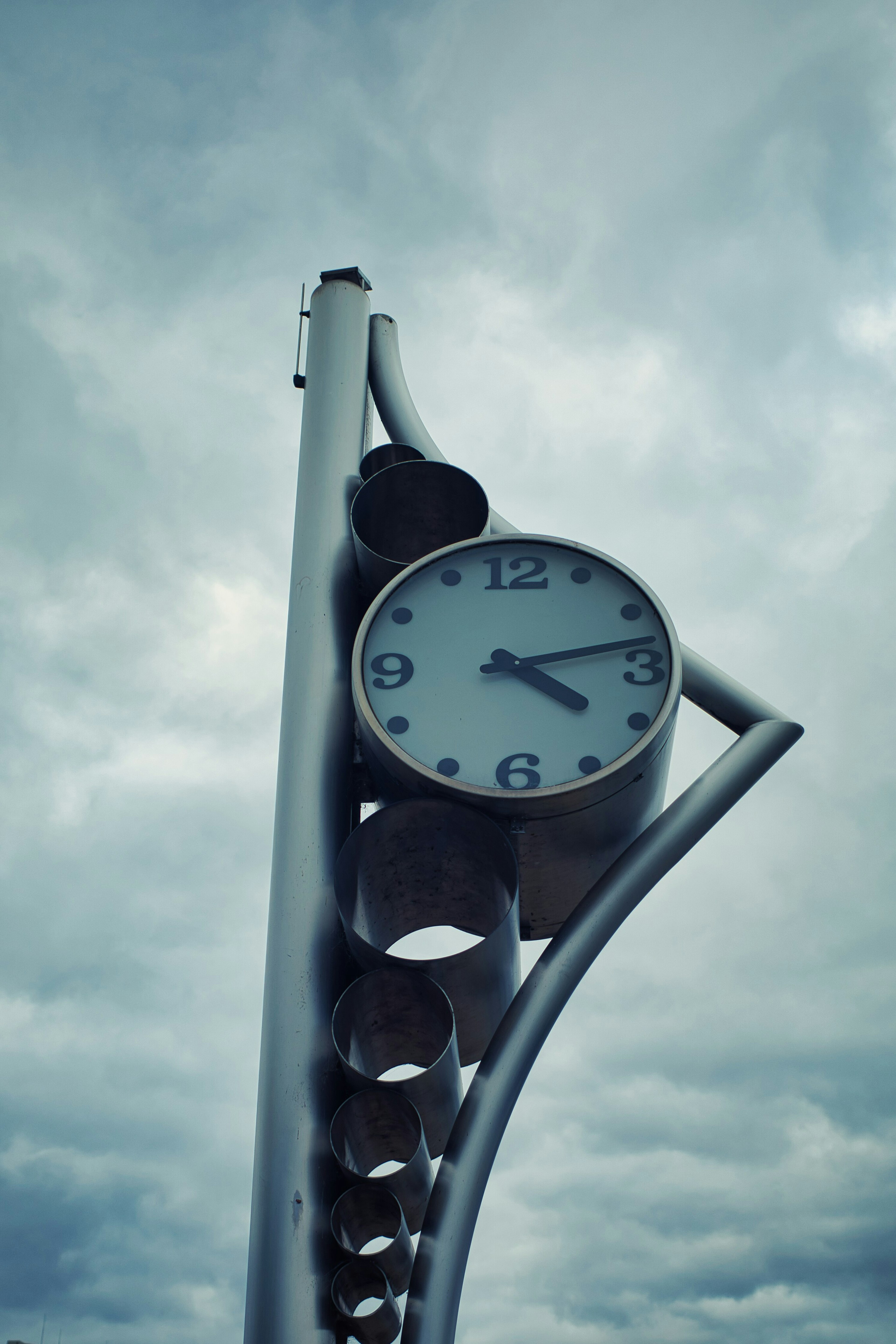 Metal structure with a clock and cloudy sky