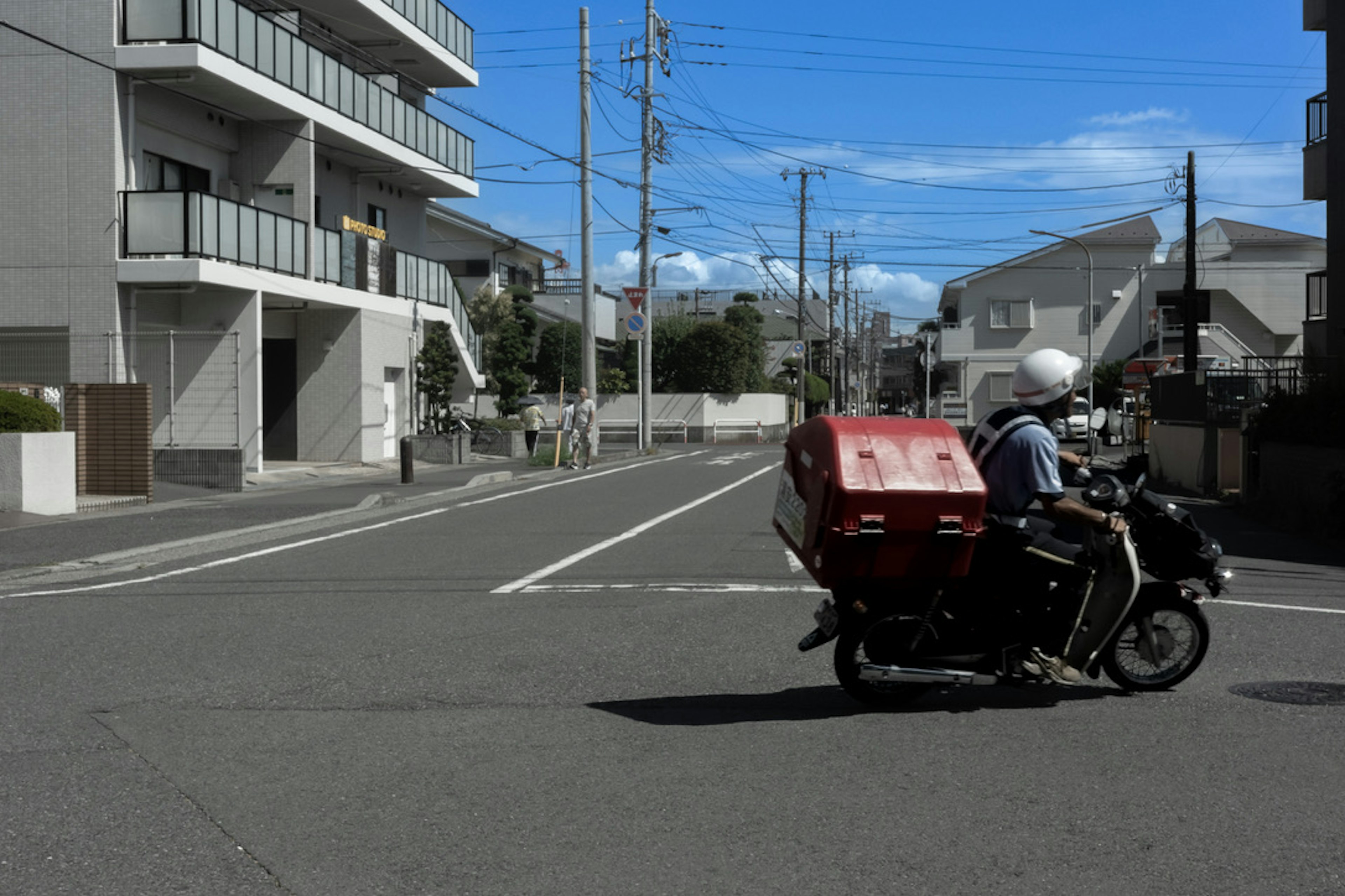 Motorcycle with red delivery box turning at the intersection