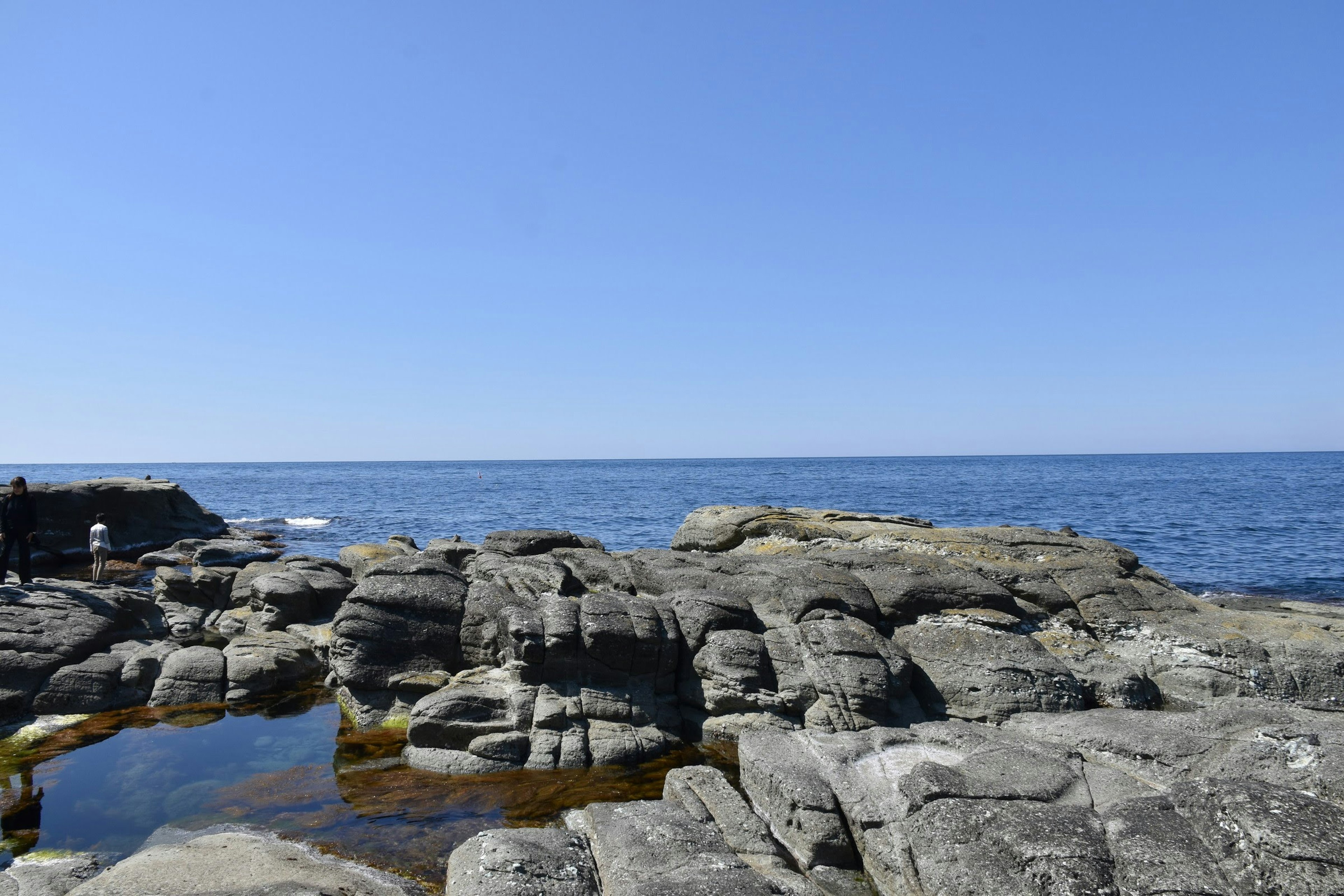 Rocky shoreline with clear blue sky and ocean