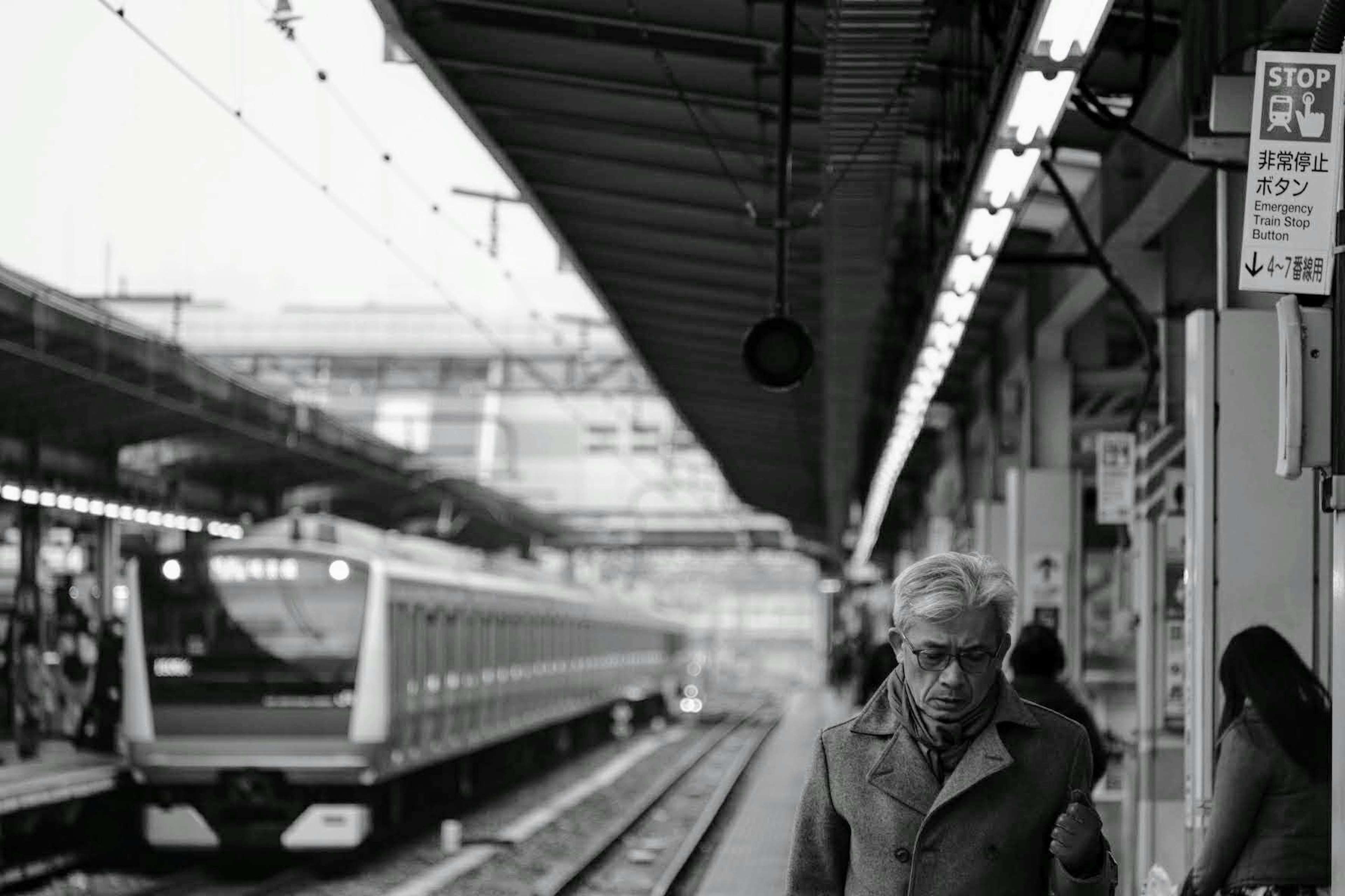 Älterer Mann, der auf dem Bahnsteig geht, mit einem herannahenden Zug