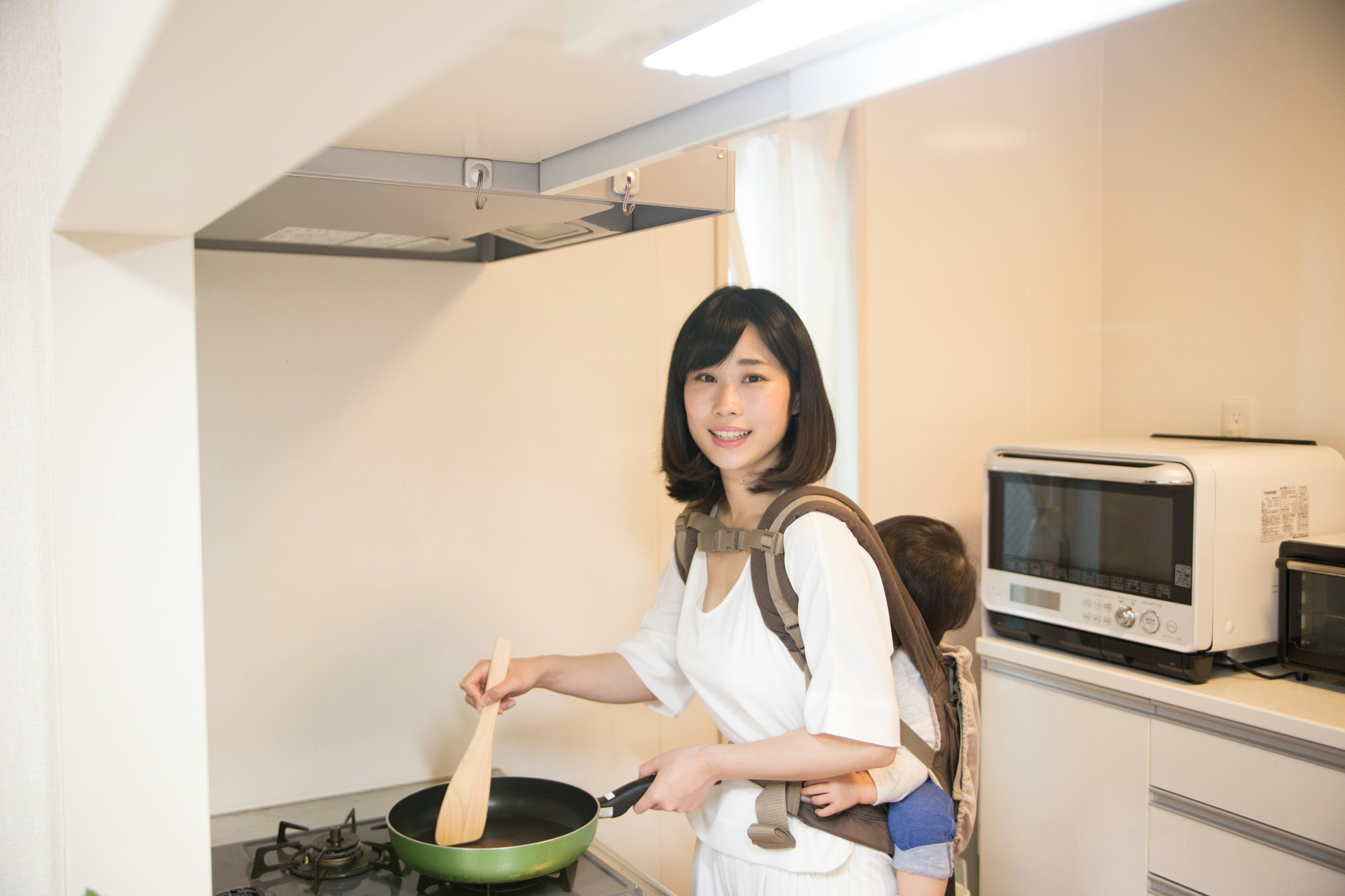 Mujer cocinando en una cocina con un niño en la espalda