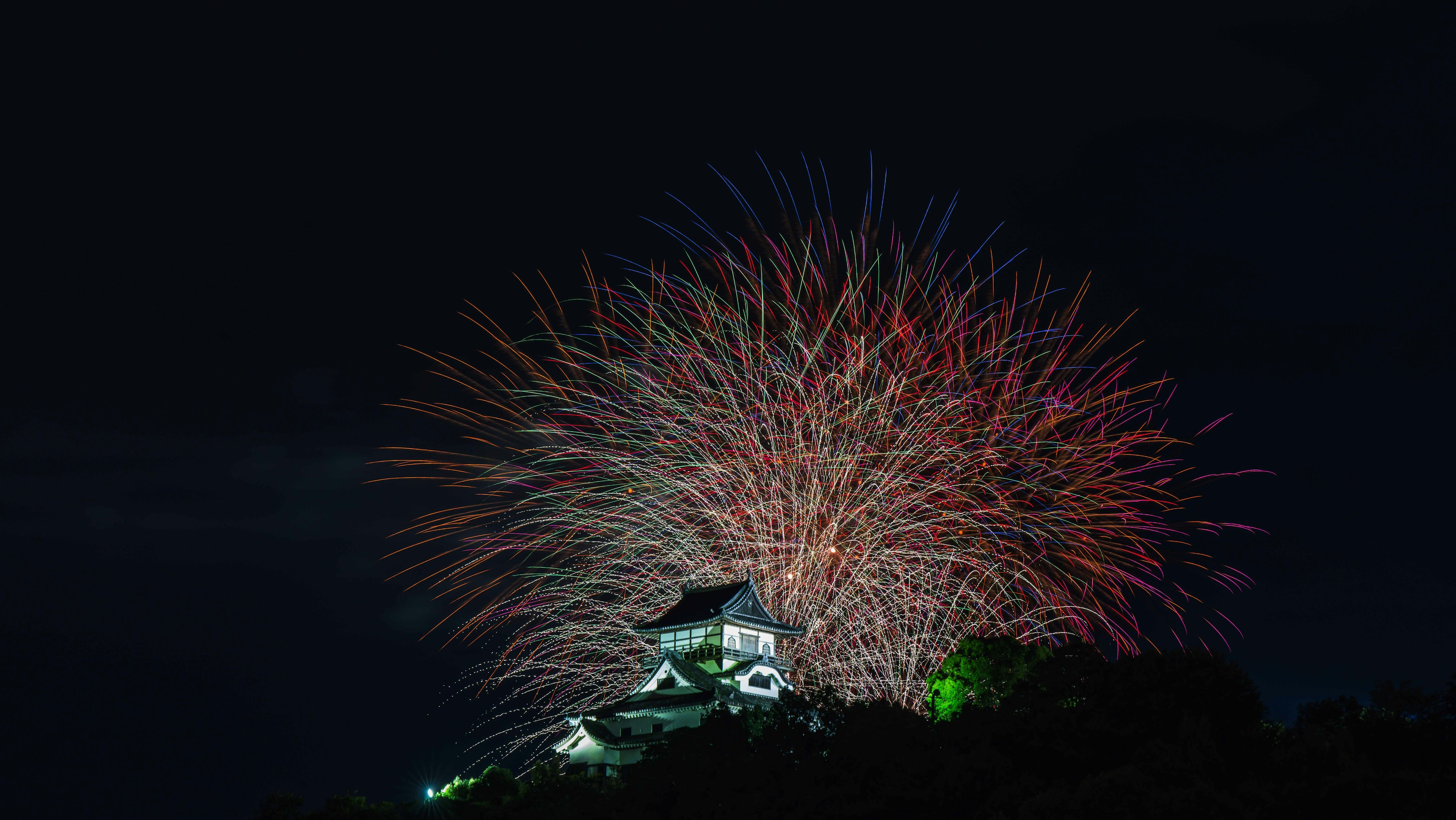 夜空に広がる色とりどりの花火と城のシルエット