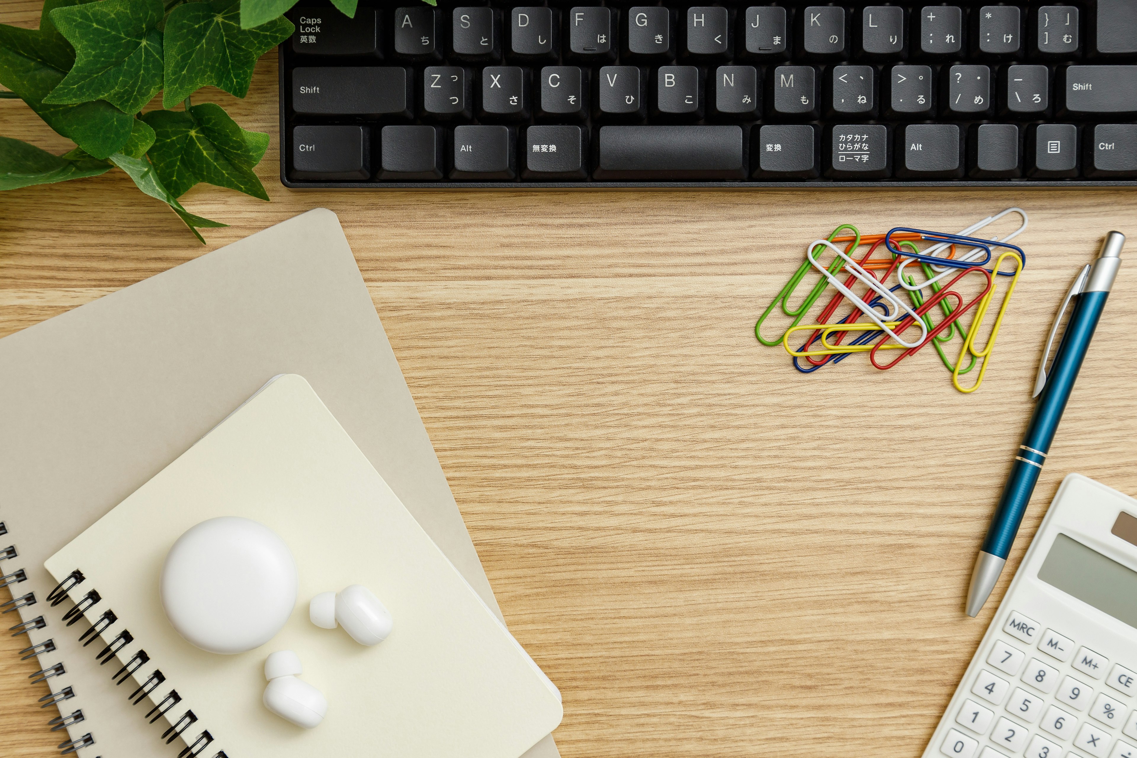 Black keyboard and stationery set on a wooden desk