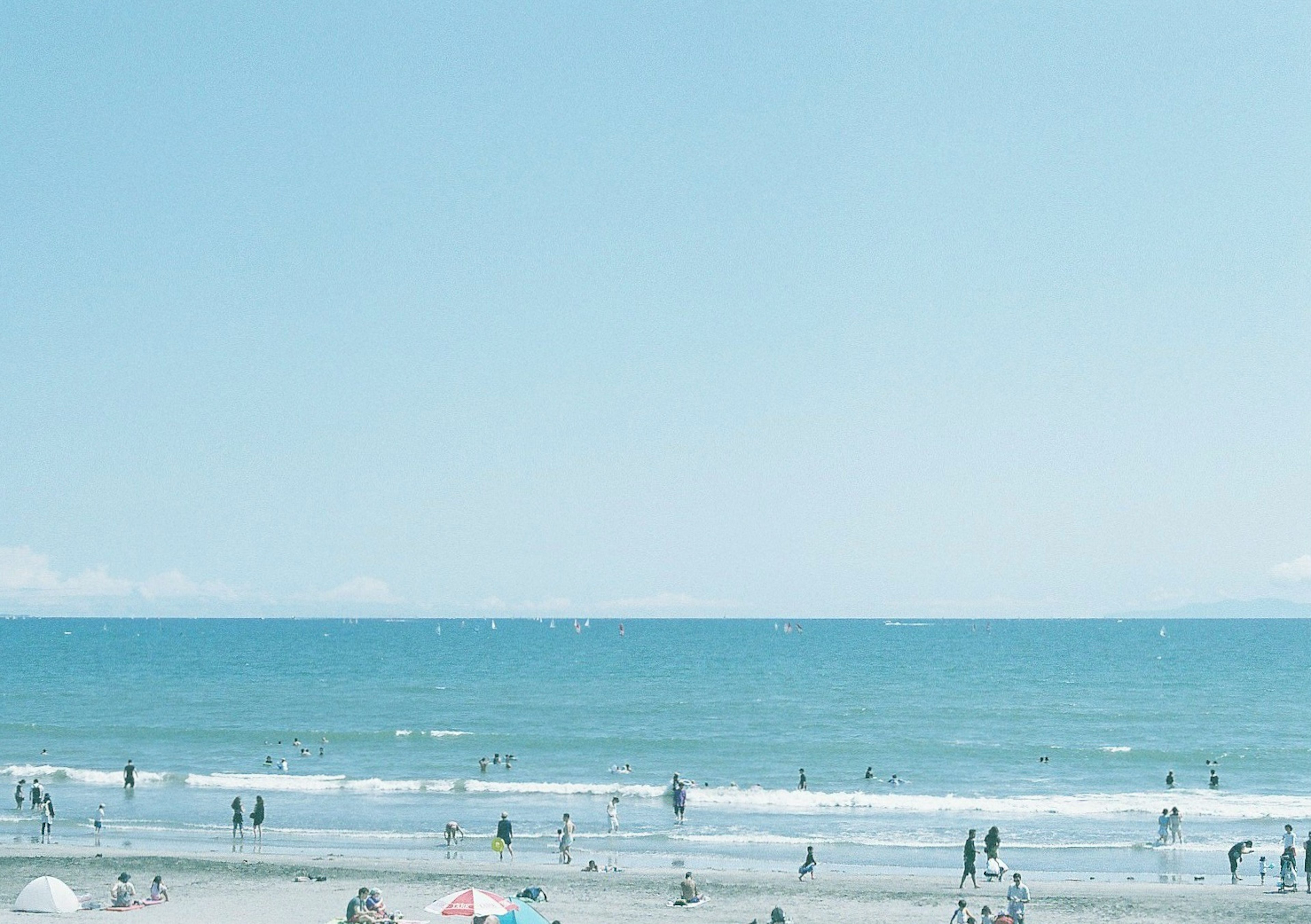 青い海と空の下に人々が集まるビーチの風景