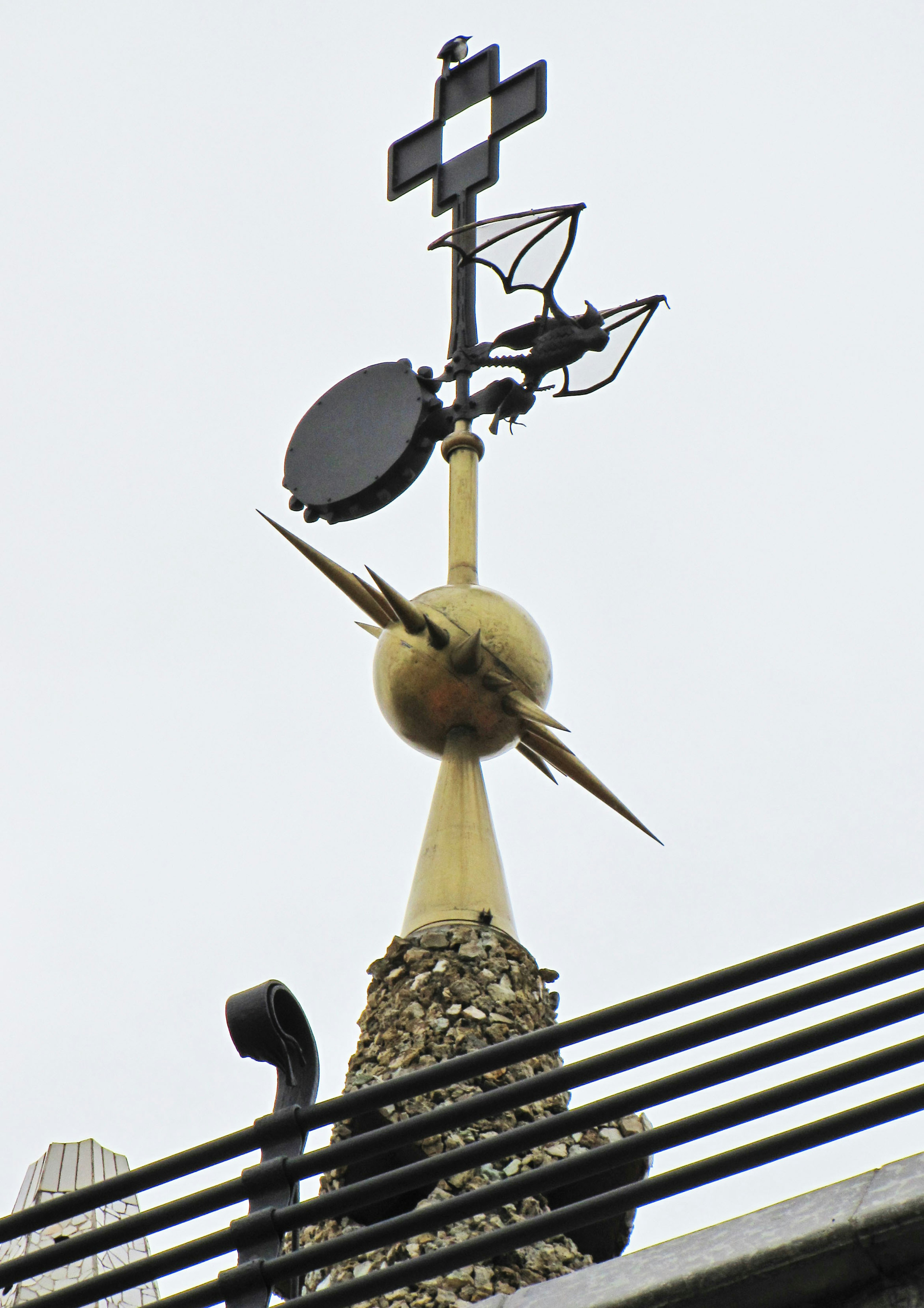 Golden weather vane with a cross design atop a building