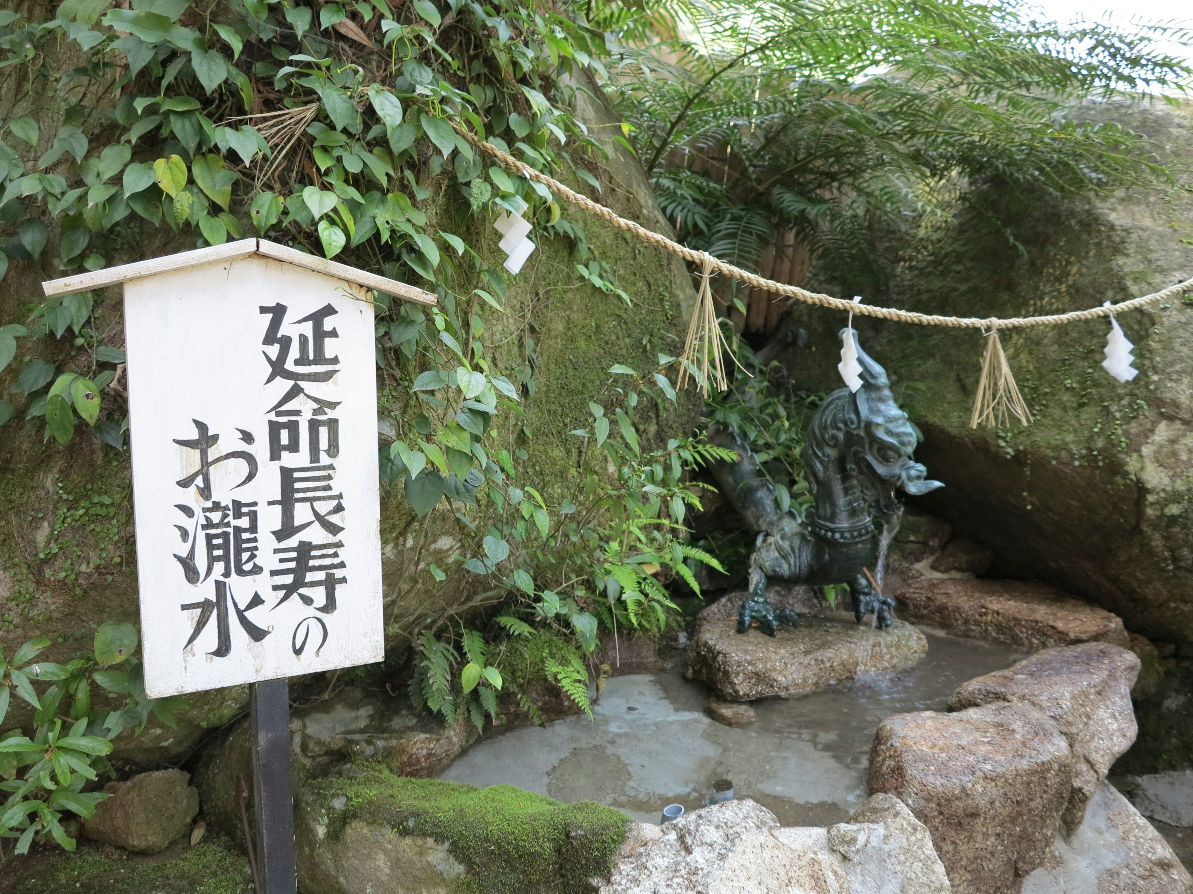 A scenic view featuring a dragon statue and a sign for a water source