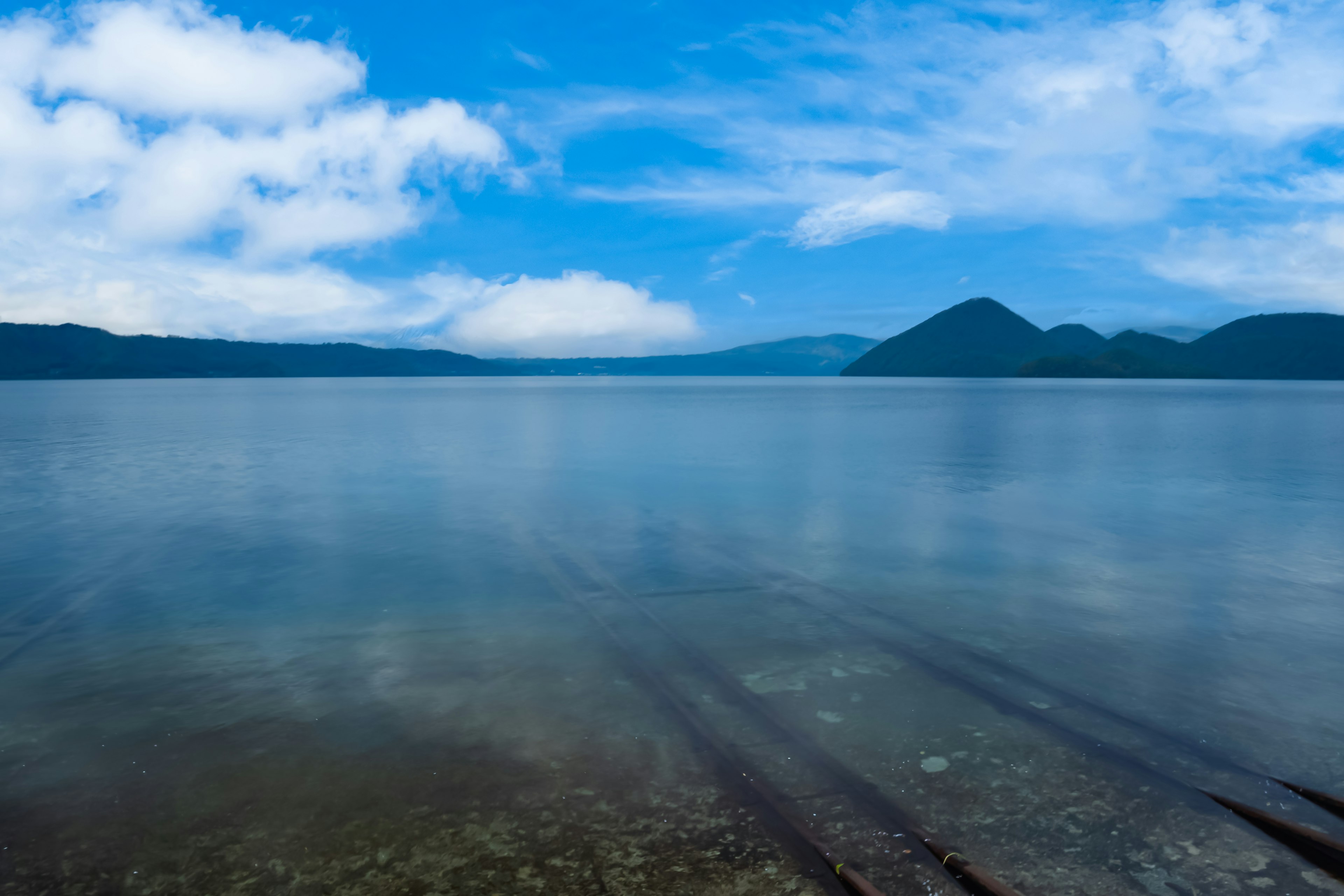 藍色湖泊的風景背景有山脈平靜的水面和天空中的雲