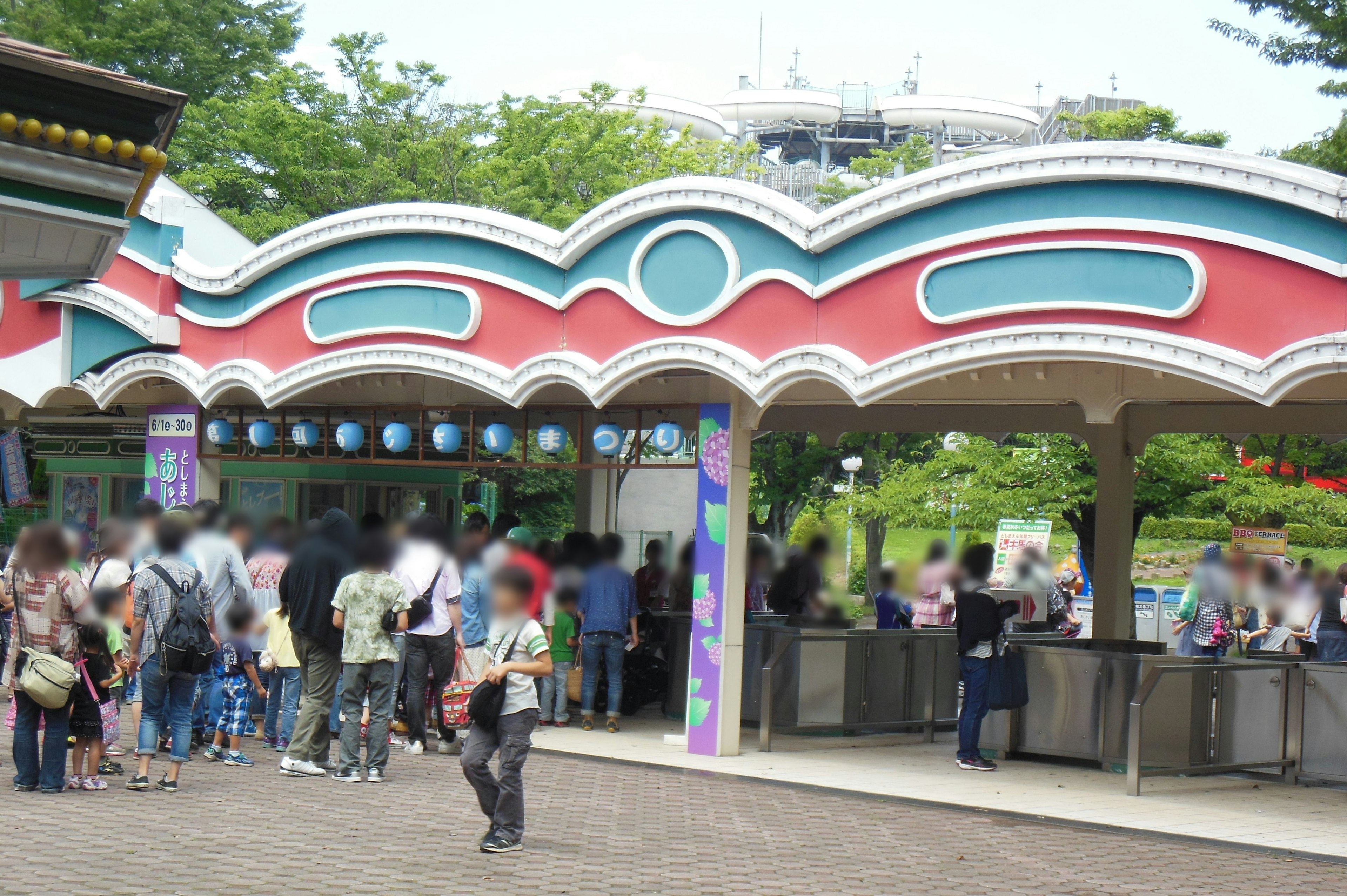 Colorful archway entrance at an amusement park with people waiting in line at the ticket counter