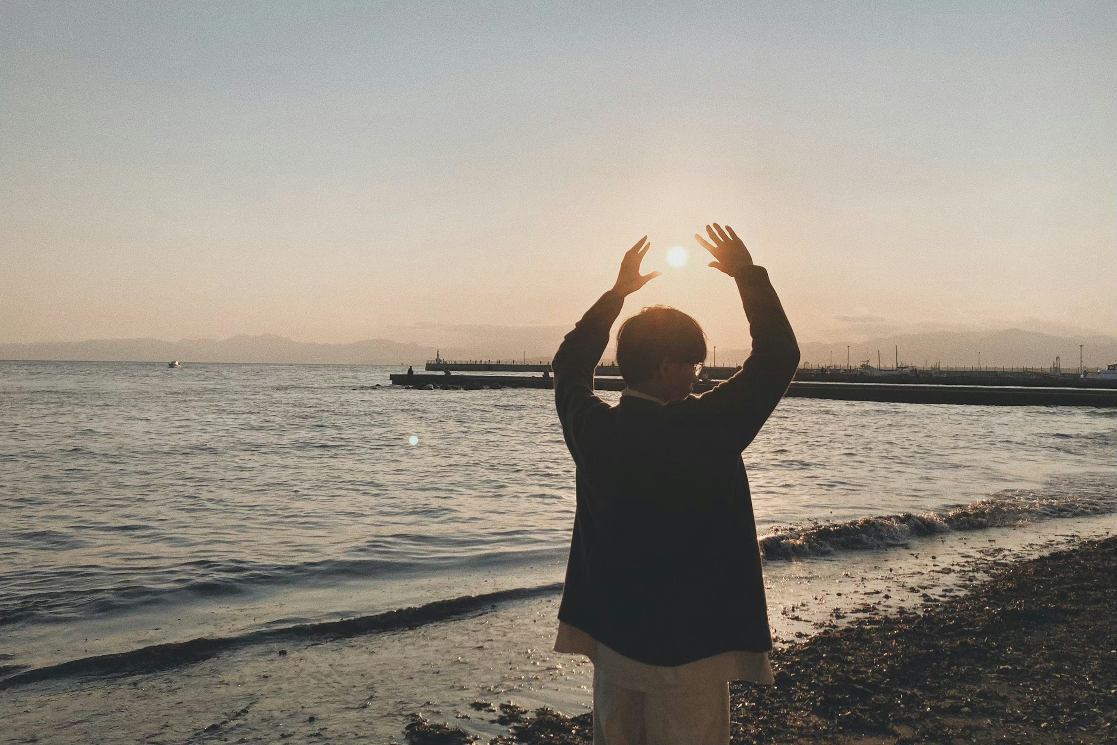 Persona che accoglie il tramonto sulla spiaggia