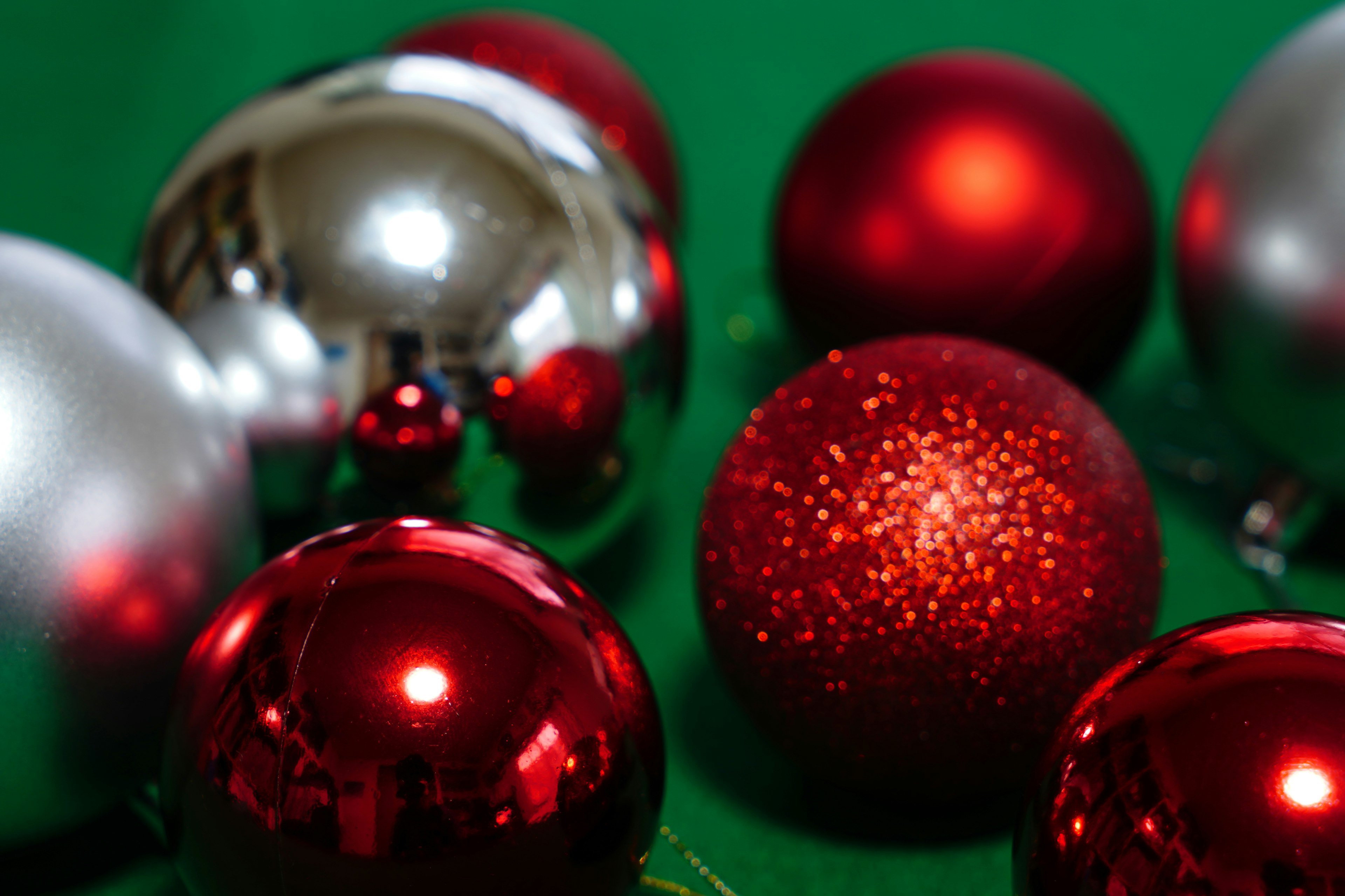 Red and silver Christmas ornaments scattered on a green background