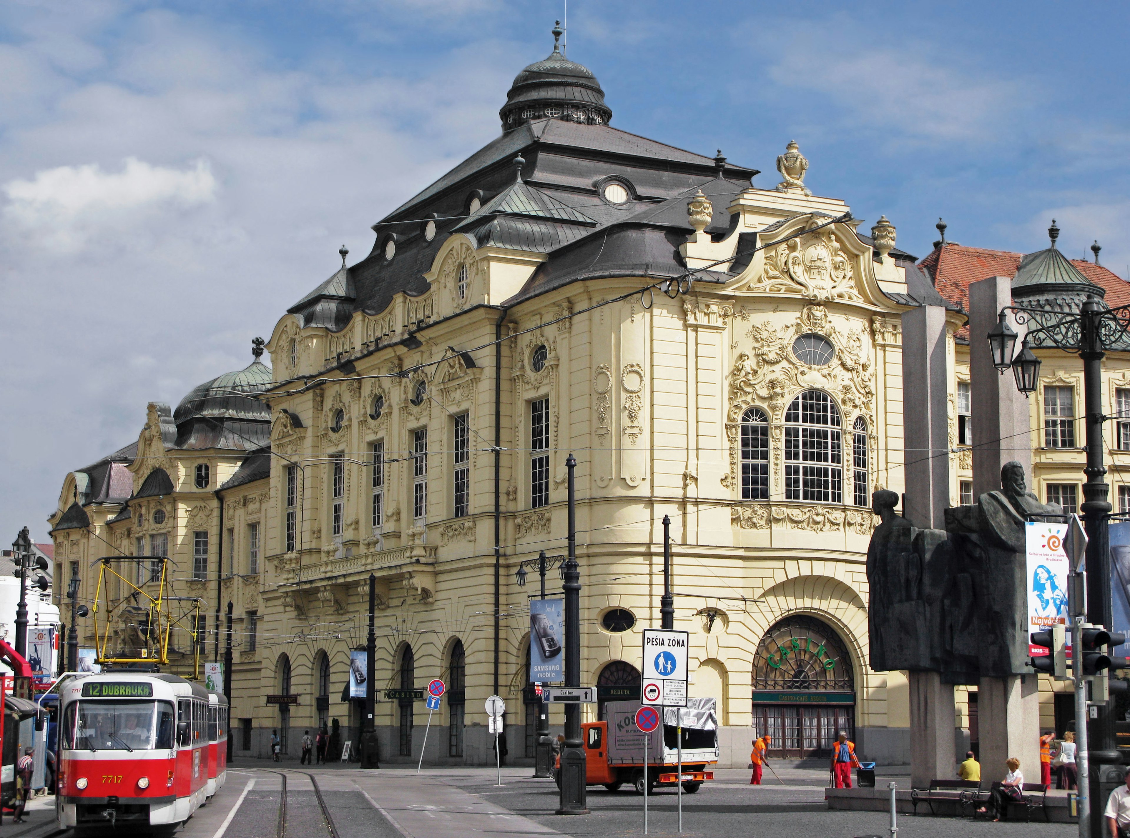 Facciata di un edificio storico con tram in un vivace contesto urbano