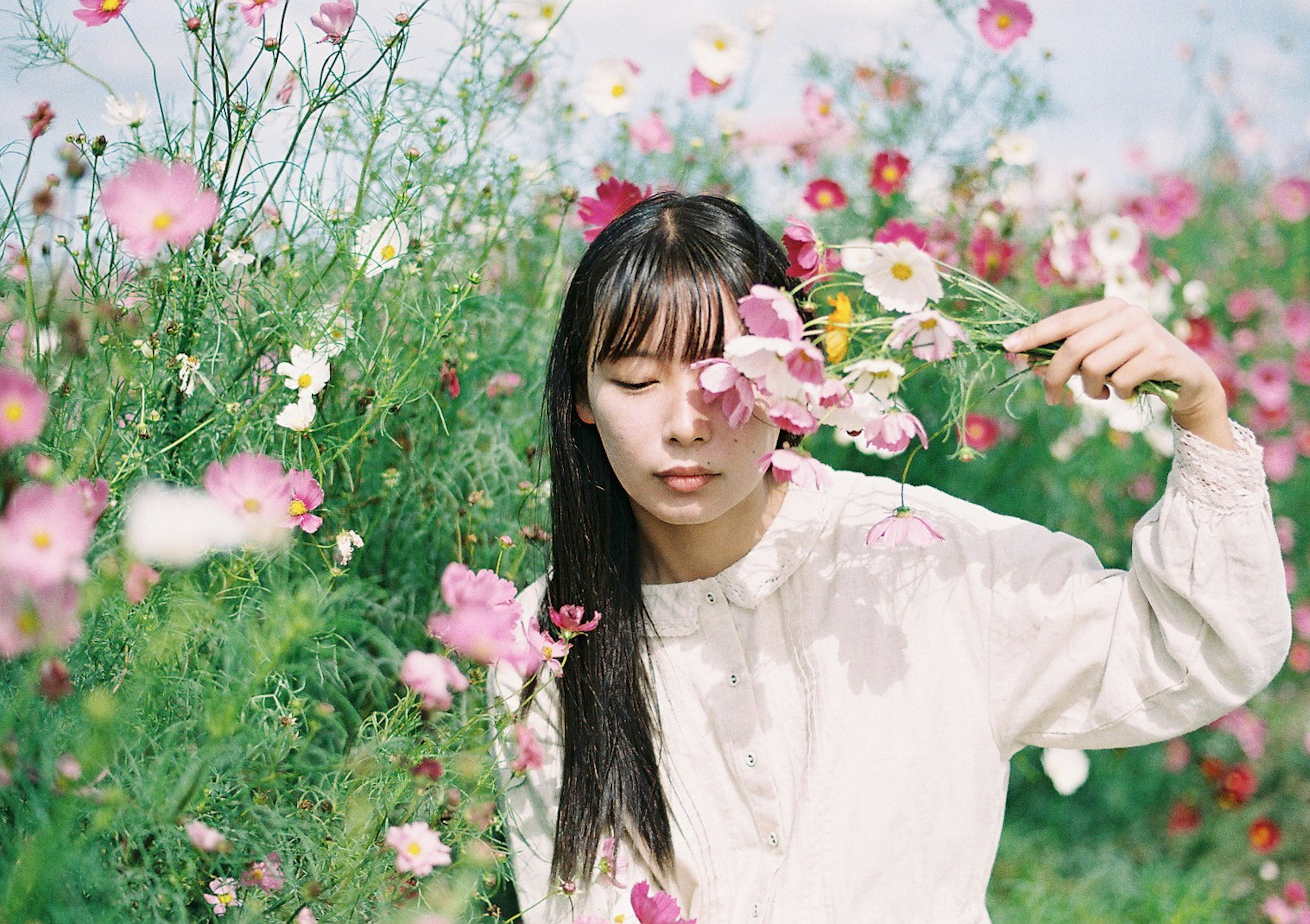 花畑の中で花を持つ女性のポートレート