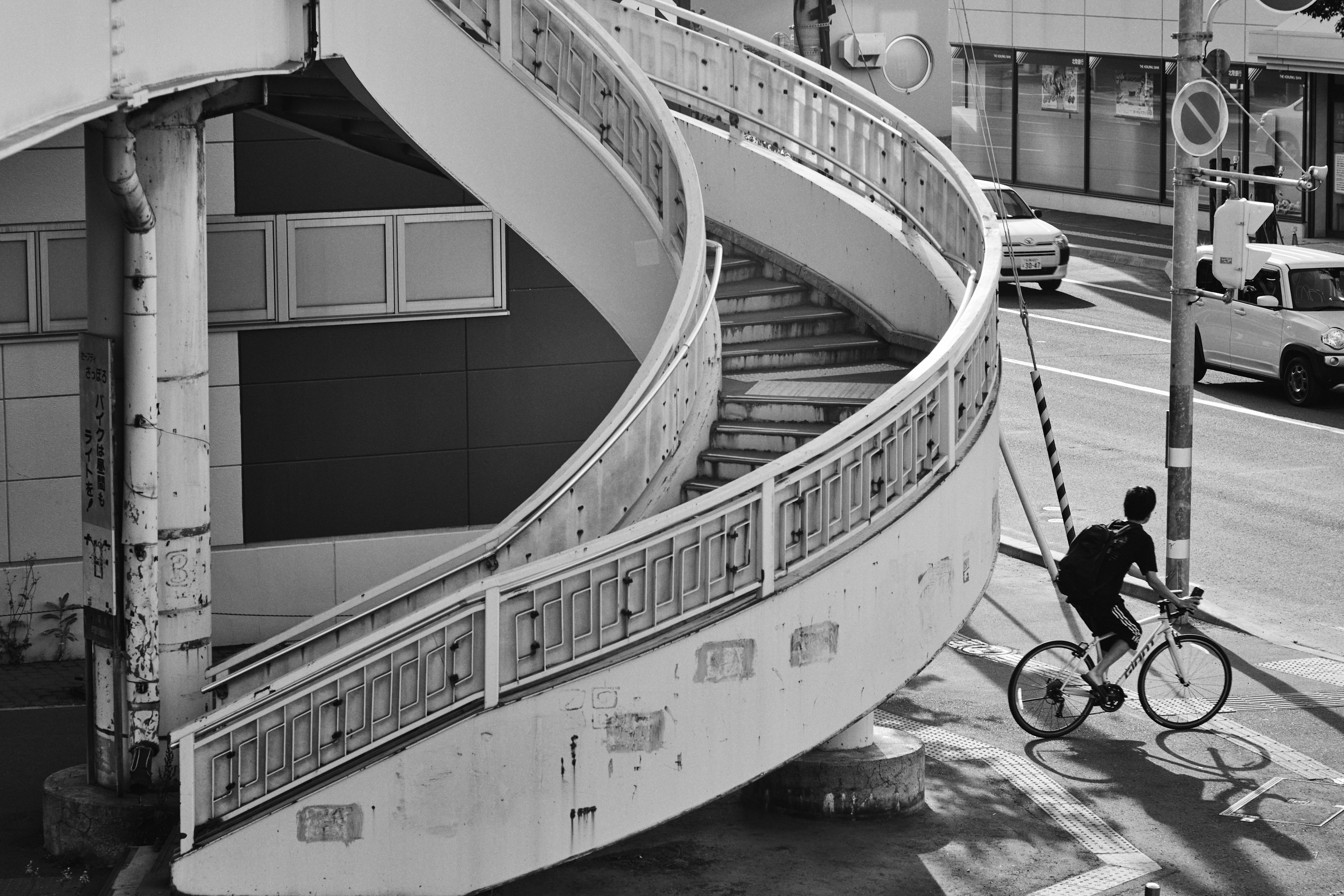 Imagen en blanco y negro con una escalera en espiral y una persona montando en bicicleta