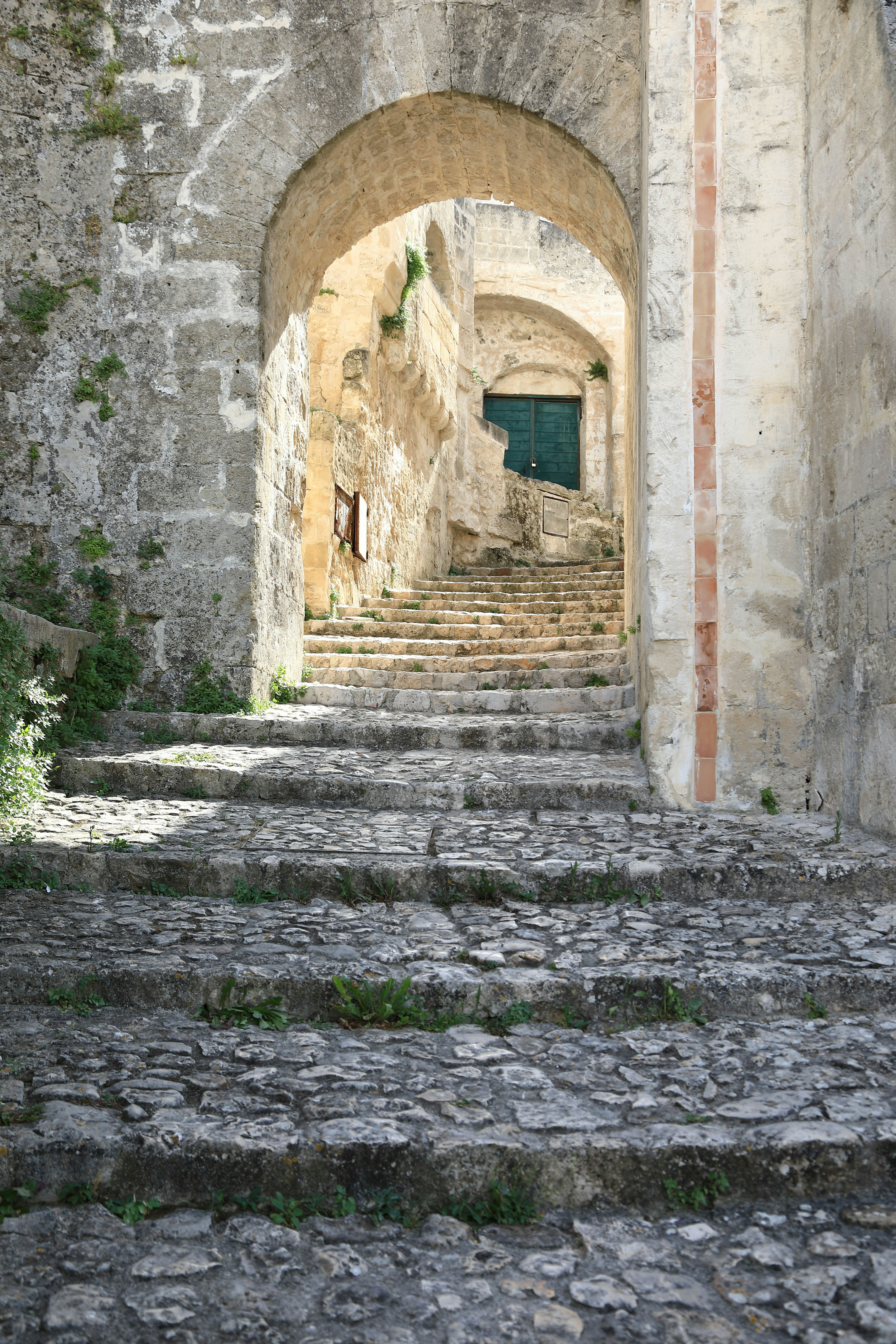 Escalera de piedra antigua que lleva a través de un arco con puerta verde