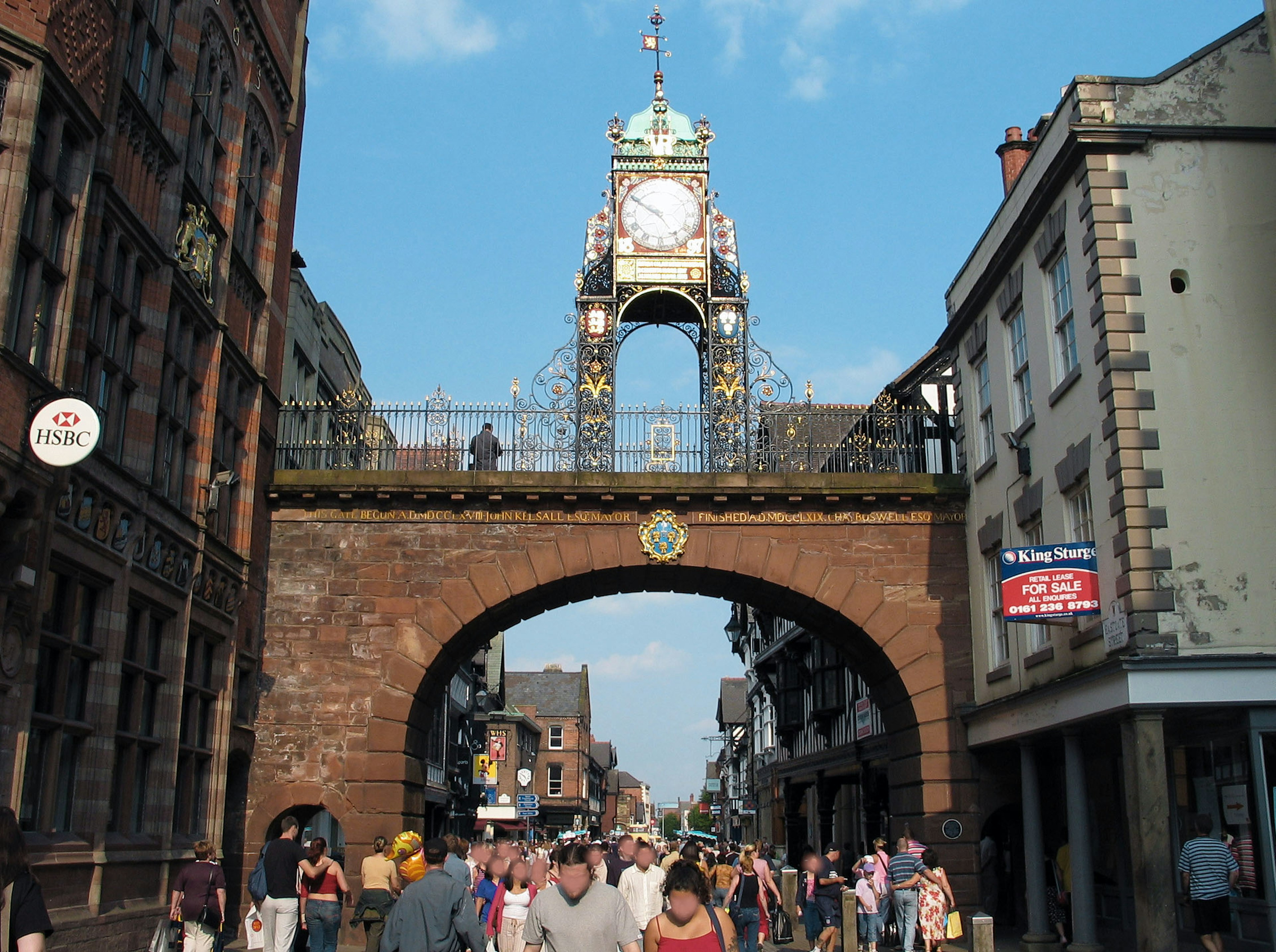 Historic clock tower in a bustling street with people walking