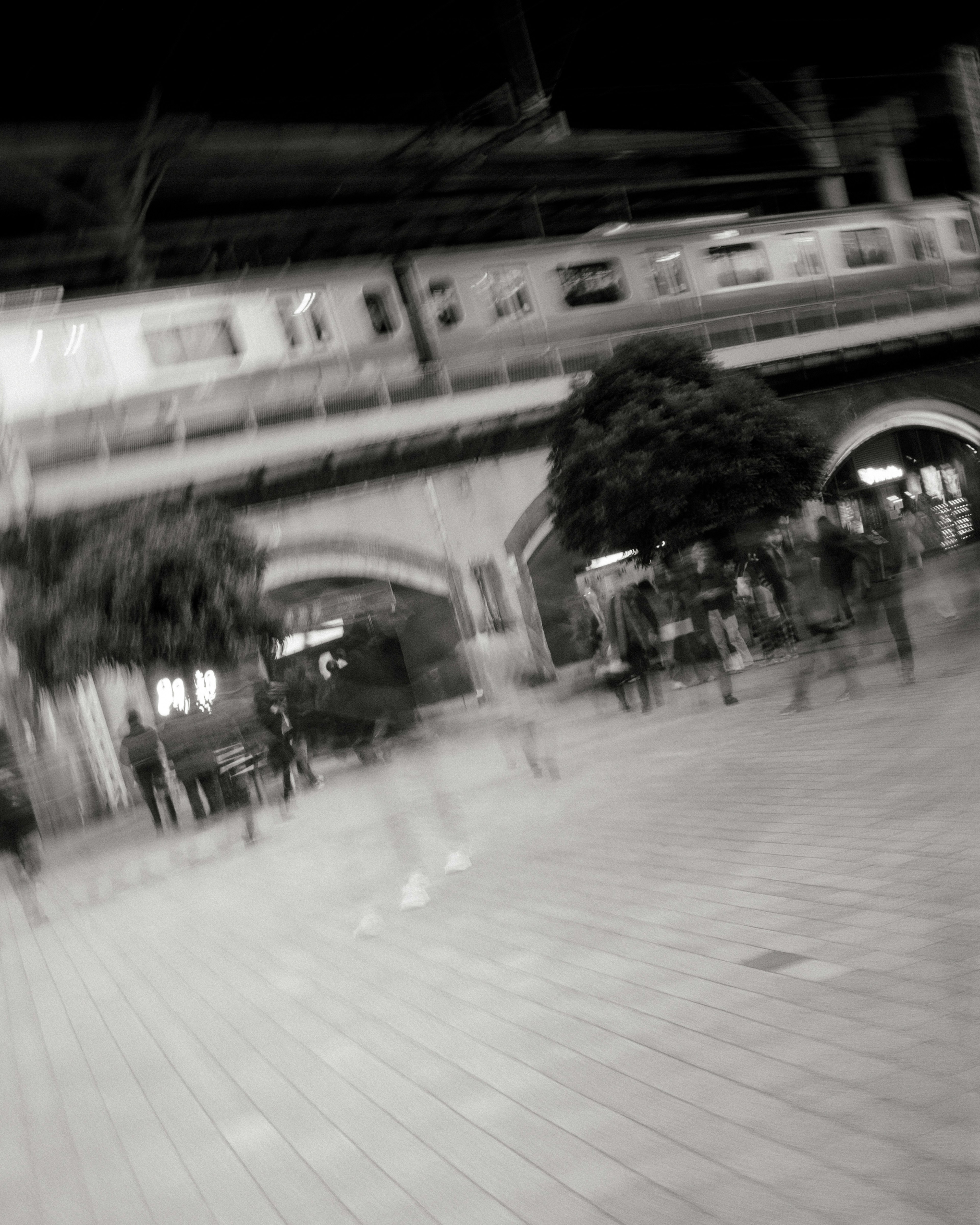 Blurred black and white photo of a city street at night with people walking