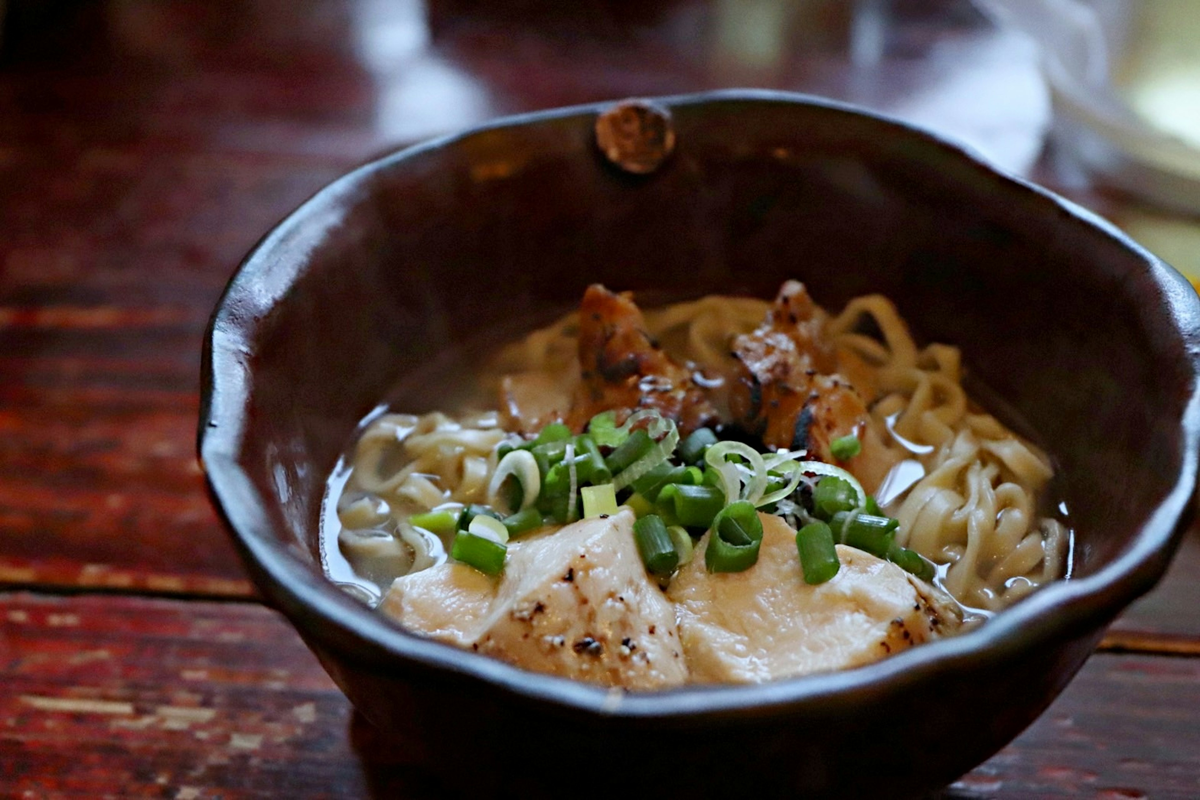 Un tazón de ramen delicioso cubierto con cebollitas verdes y chashu